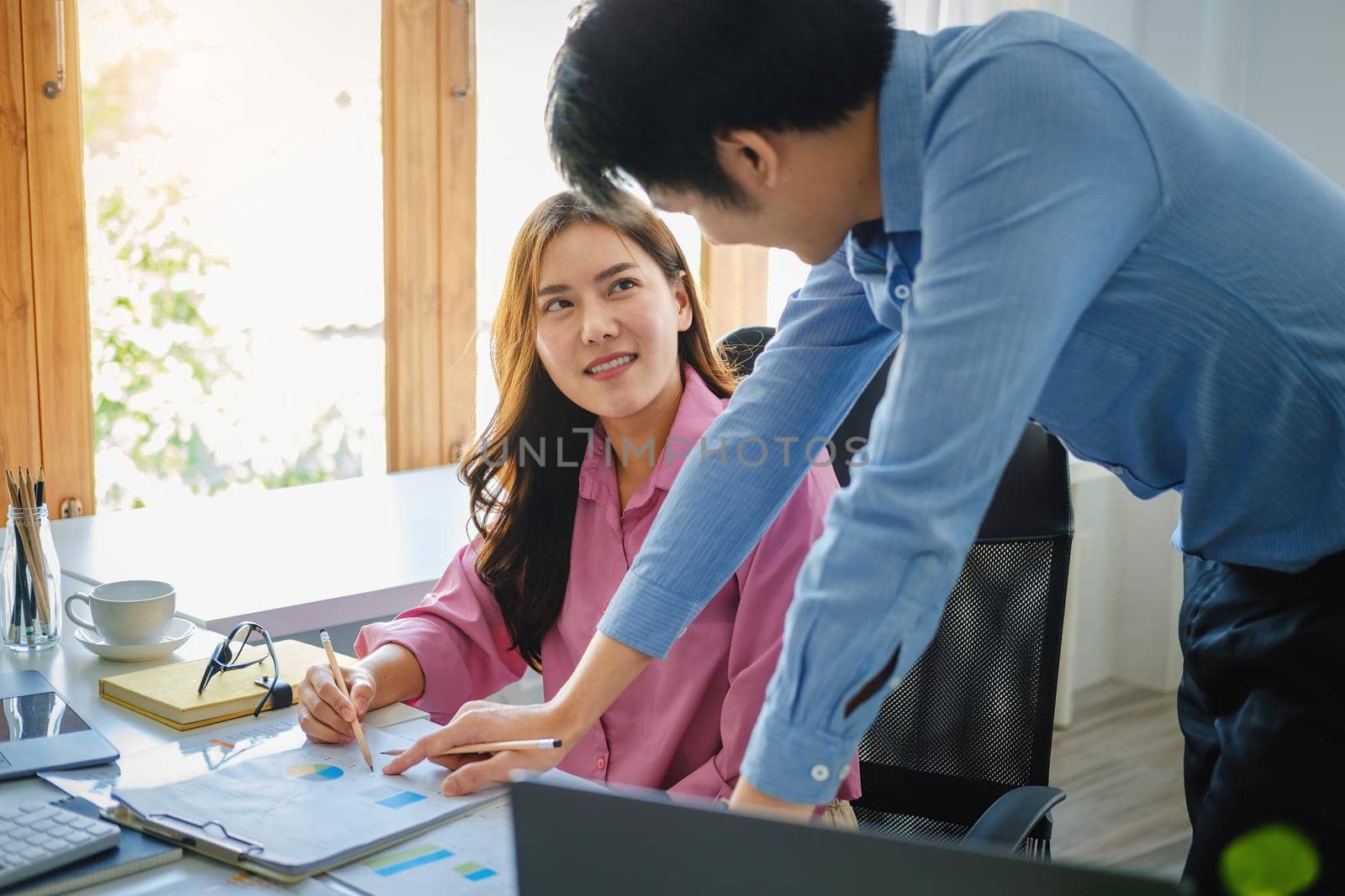 negotiation, analysis, discussion,asian male economist pointing out a document explaining the investment finance program to the company owner to plan marketing and hedging business risks. by Manastrong