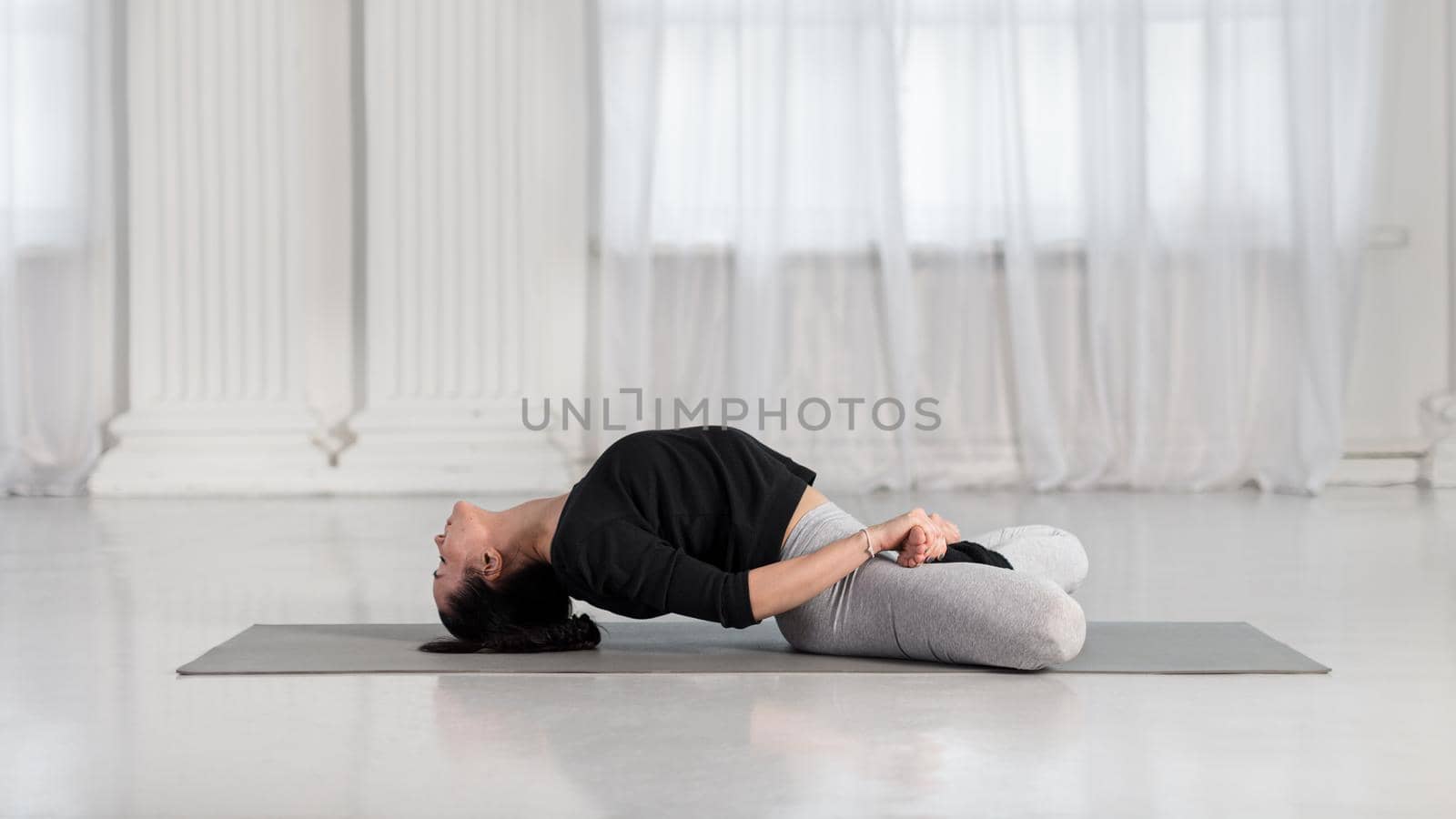 Young asian woman practicing in a yoga studio. Fish pose, or Matsyasana with lotus legs. by apavlin