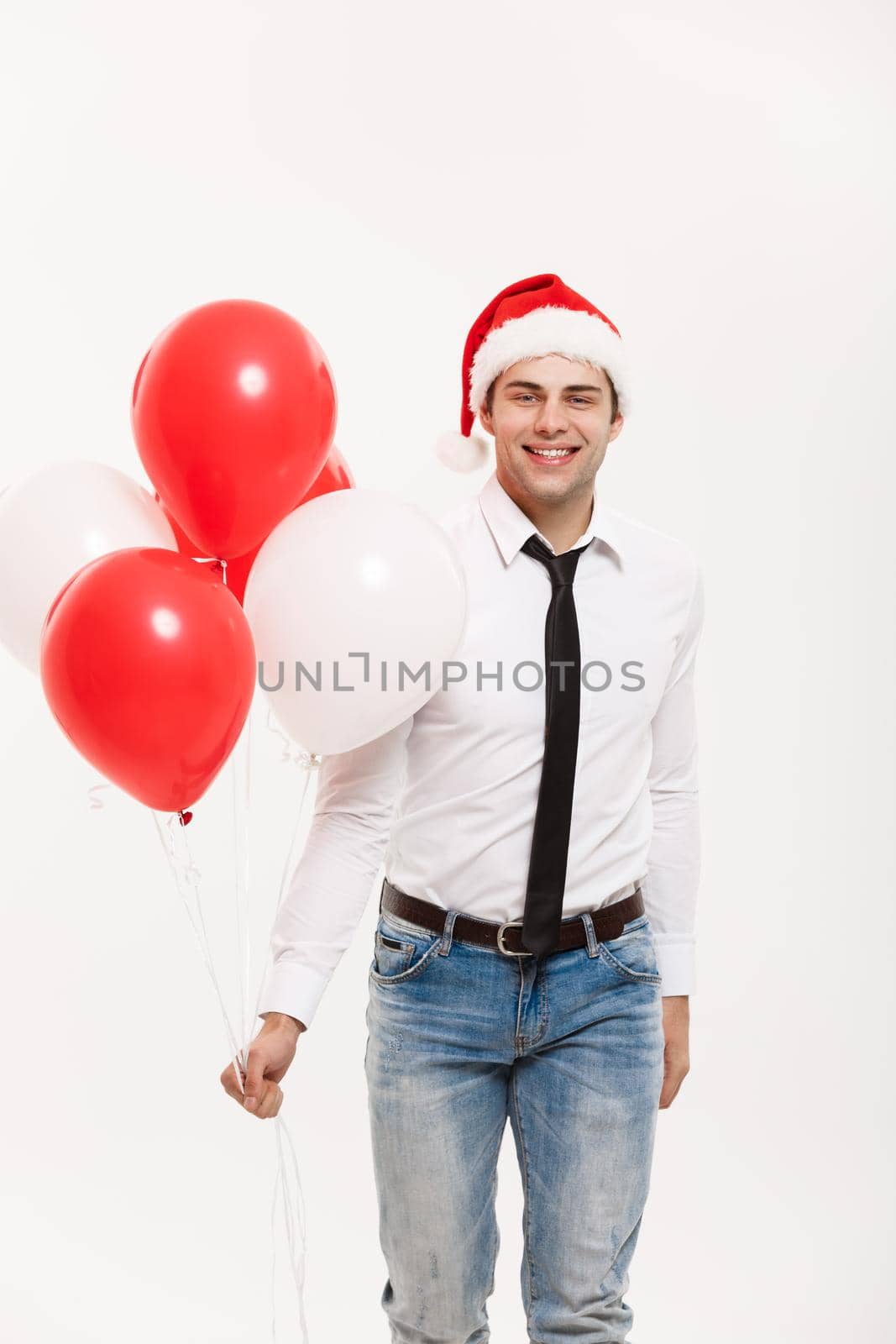 Christmas Concept - Handsome happy Business man walking with red balloon celebrate merry christmas and happy new year wear santa hat. by Benzoix
