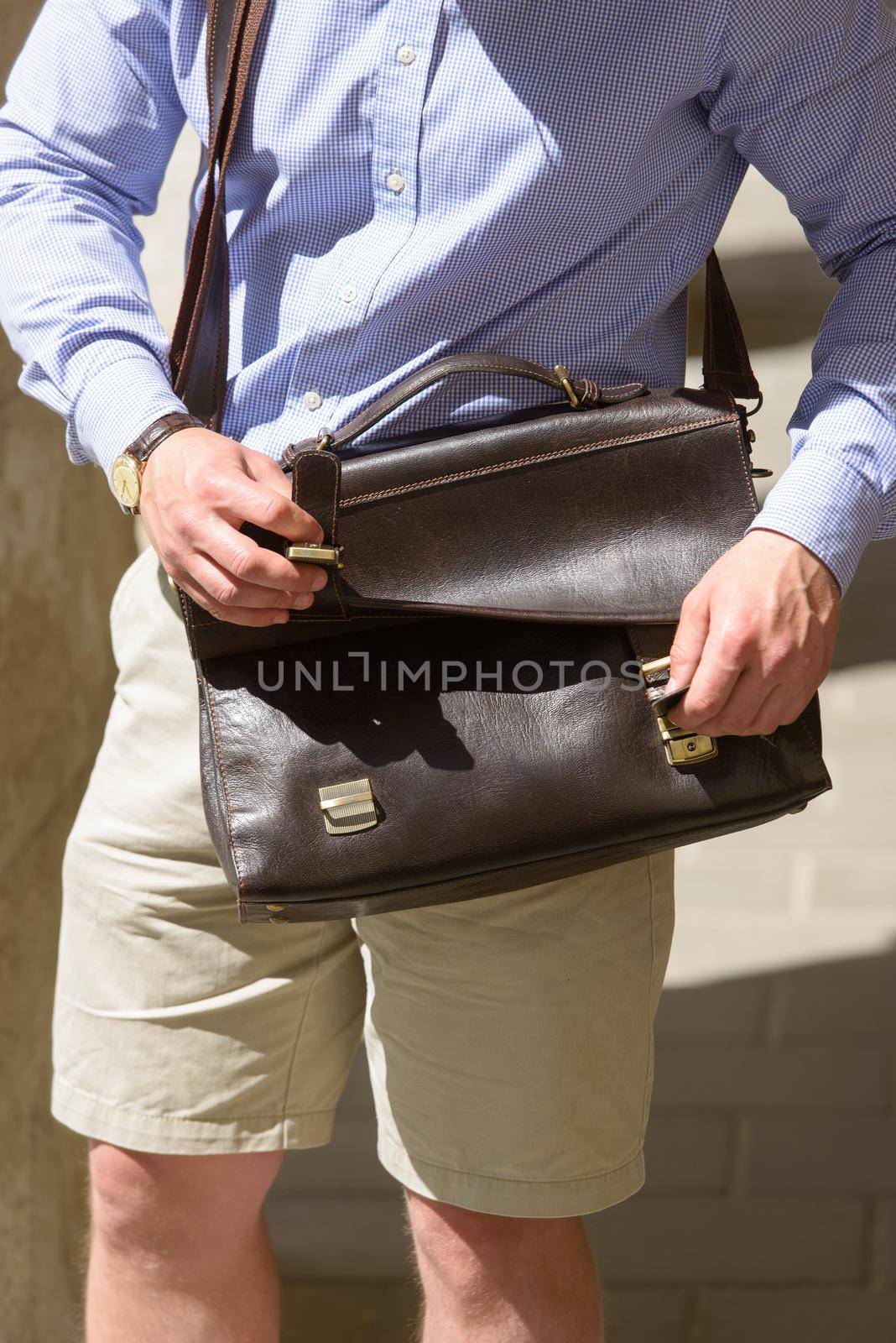 Part photo of a man with a brown leather briefcase with antique and retro look. Outdoors photo by Ashtray25