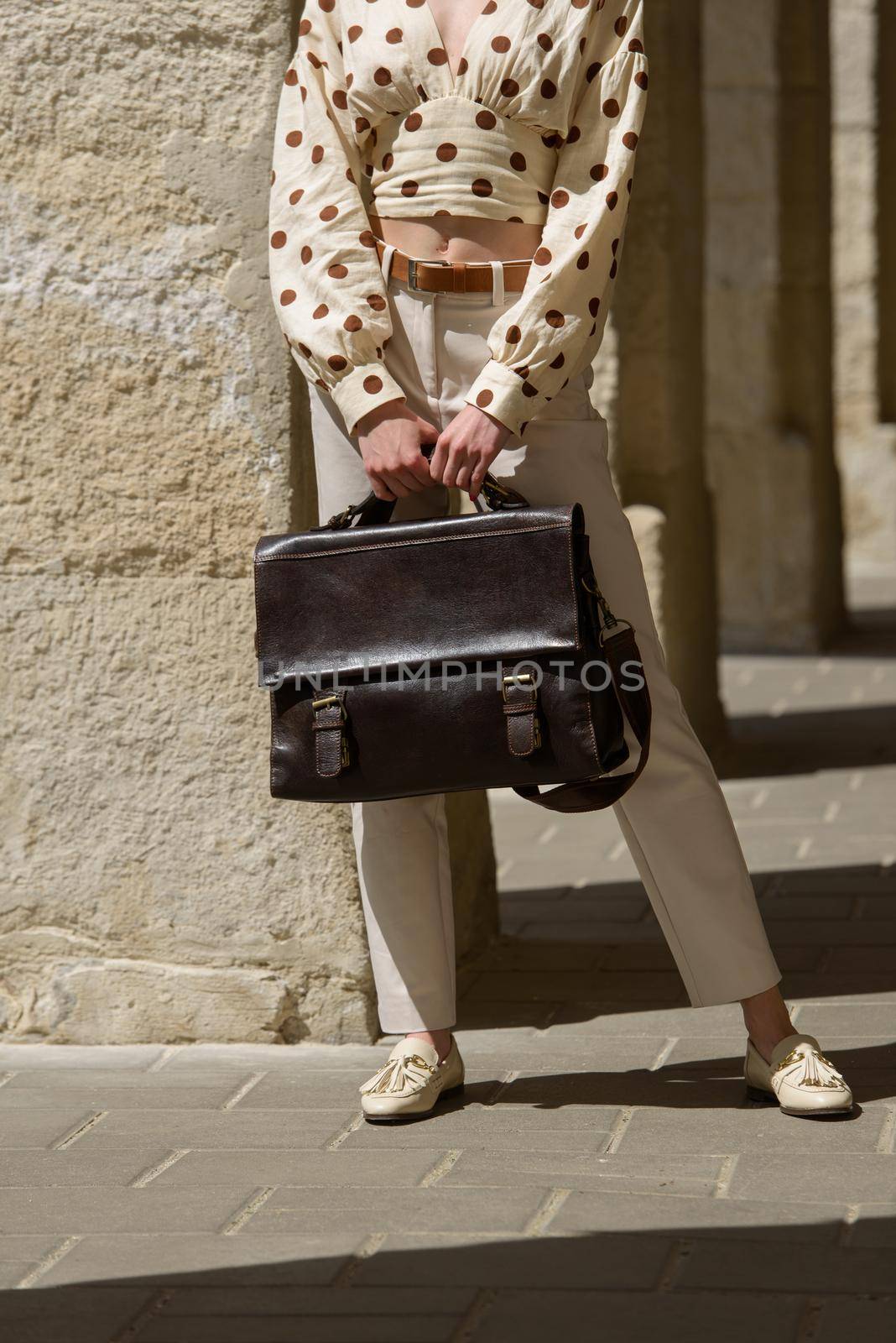 Woman with a brown leather briefcase with antique and retro look. Outdoors photo.