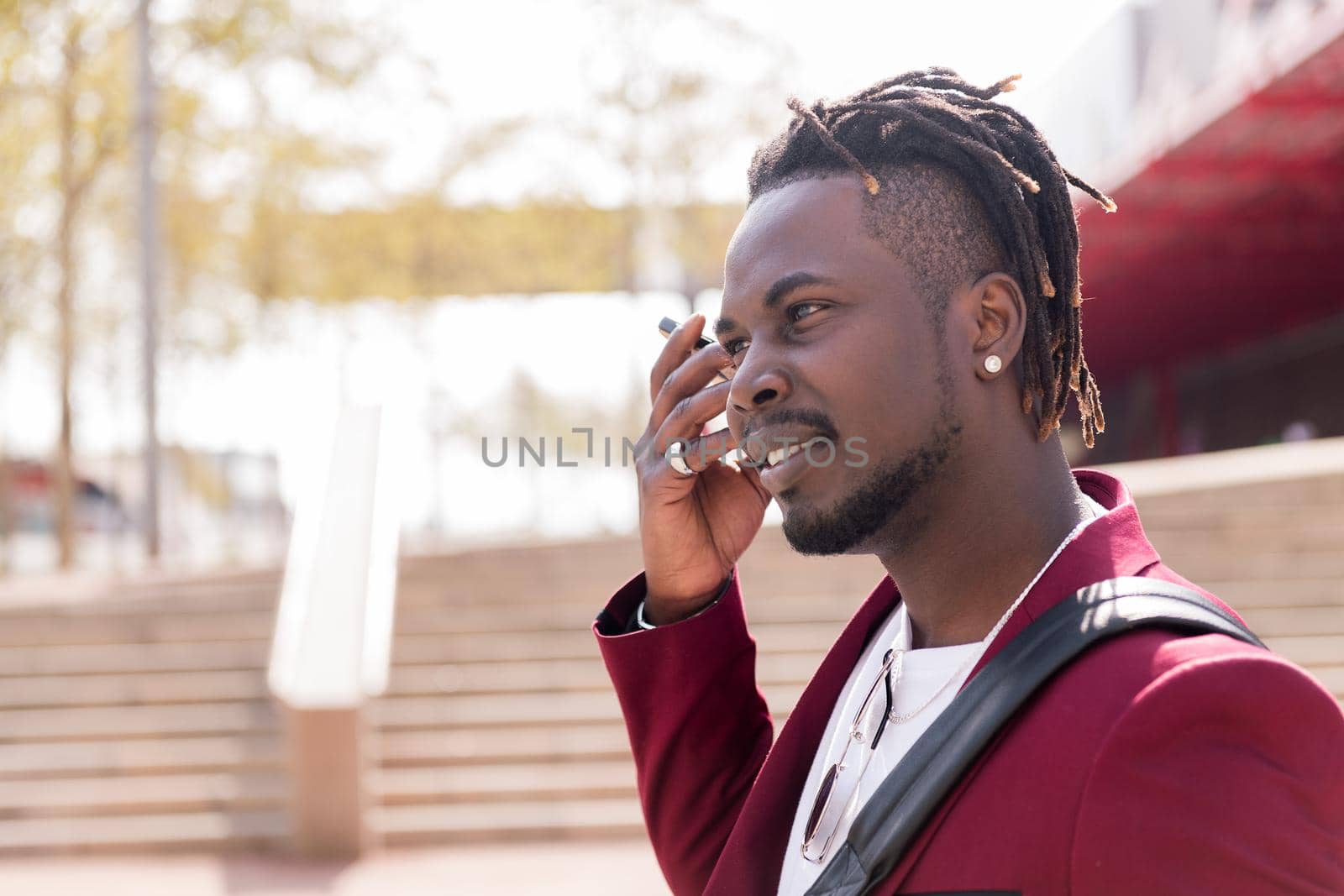 elegant black businessman listens to a voice message on his smart phone while walking through the city, copy space for text, concept of technology and communication