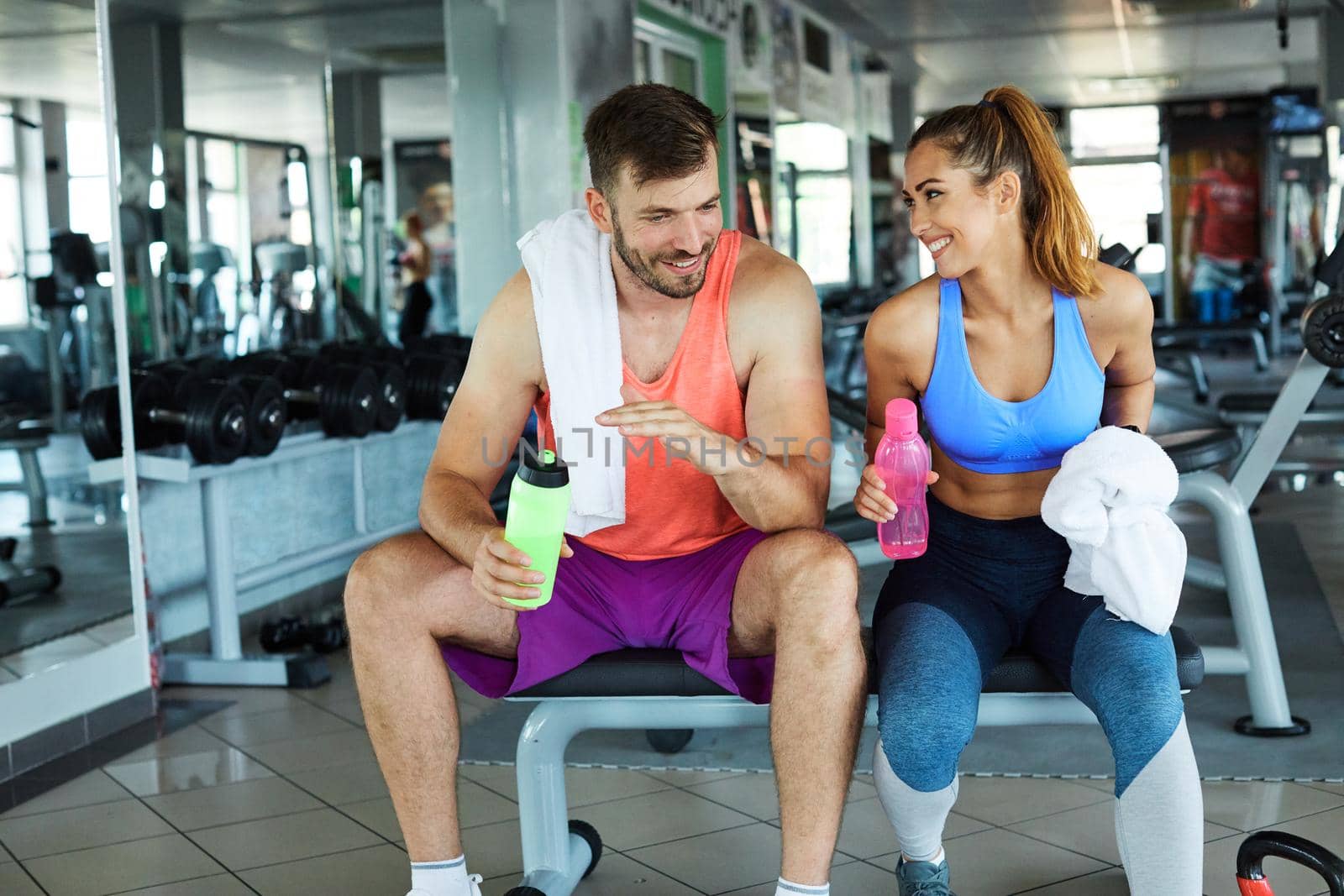 Happy young couple resting after the exercise in the gym