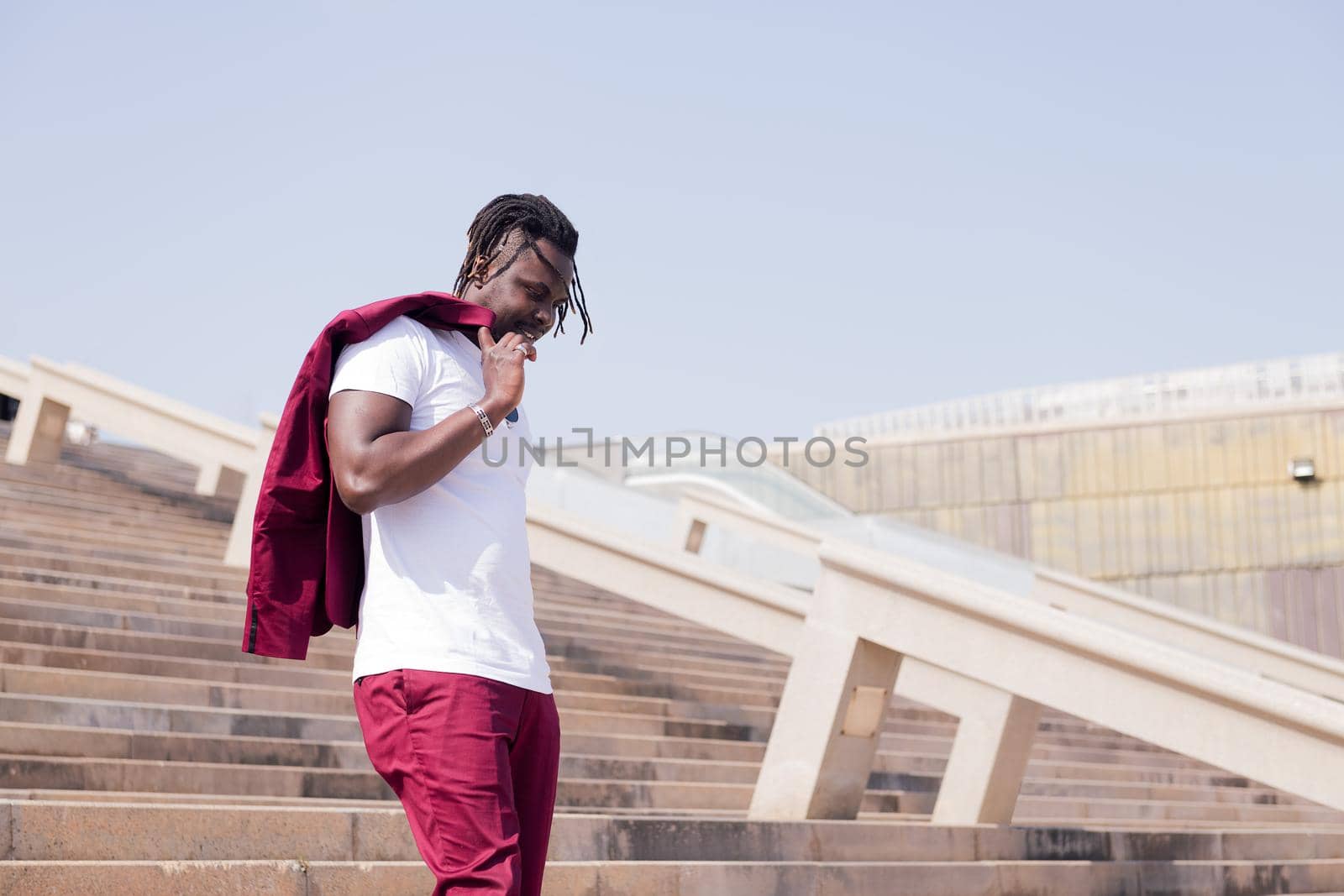 stylish black man walking down a city staircase with his blazer over his shoulder, urban lifestyle concept, copy space for text