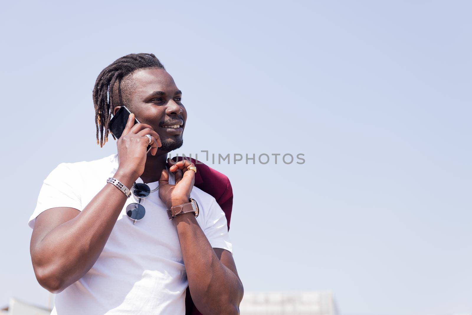 smiling black man talking by phone outdoors, concept of technology and city lifestyle, copy space for text