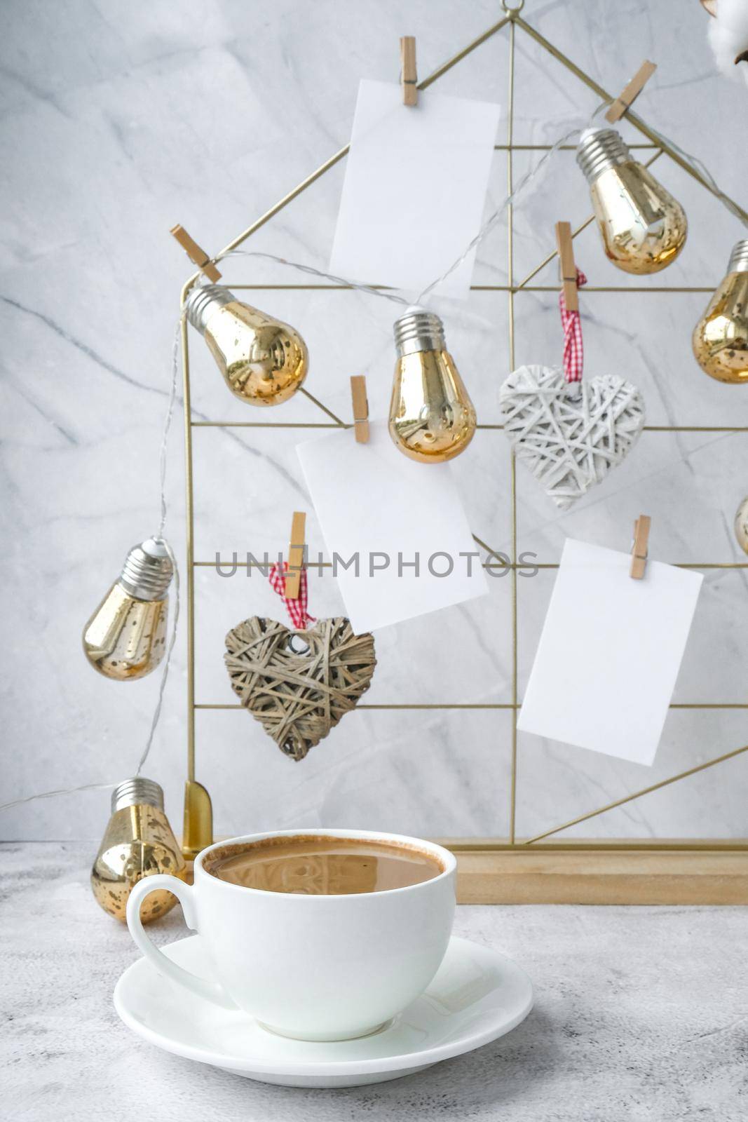 White home office room interior, bloggers workplace. Cup of coffee. Mood board with postcards and reminders mockup. Cotton branches in a vase, interior decoration. Feminine hipster office table decoration. Freelance workplace