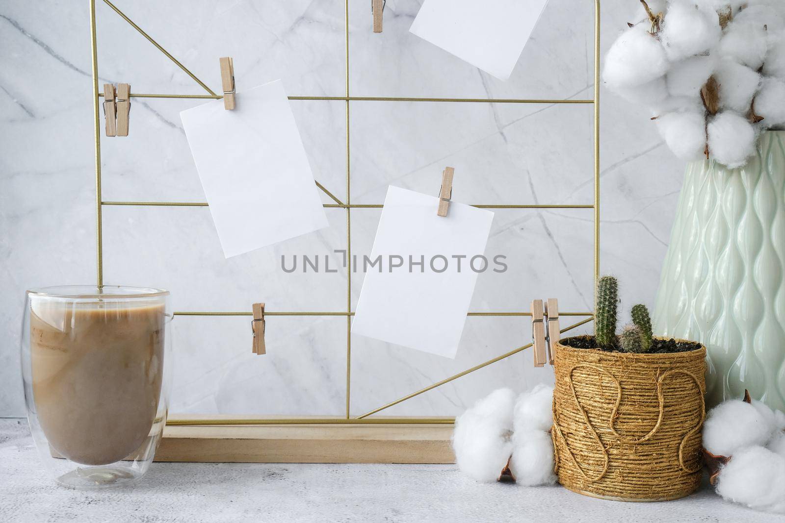 White home office room interior, bloggers workplace. Cup of coffee. Mood board with postcards and reminders mockup. Cotton branches in a vase, interior decoration. Freelance workplace by anna_stasiia