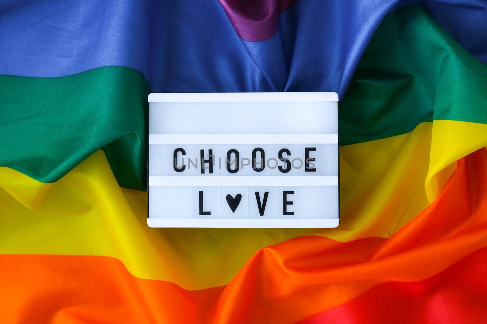 Rainbow flag with lightbox and text CHOOSE LOVE. Rainbow lgbtq flag made from silk material. Symbol of LGBTQ pride month. Equal rights. Peace and freedom. Support LGBTQ community