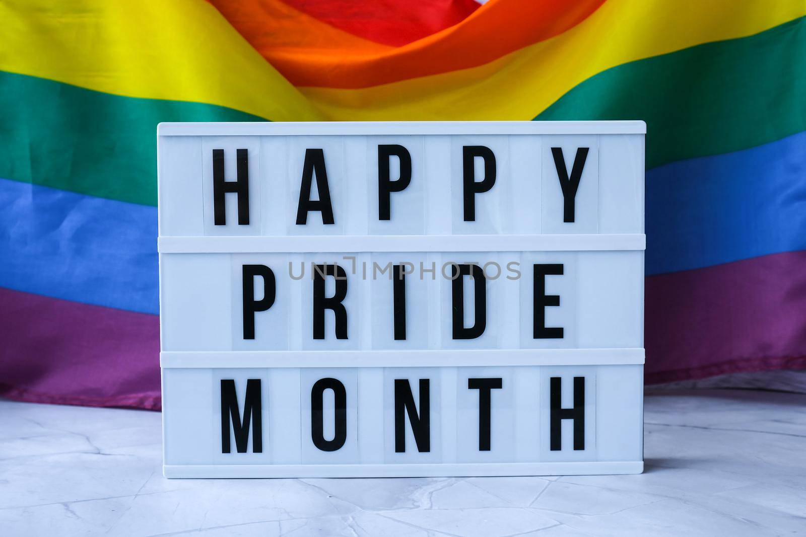 Rainbow flag with lightbox and text HAPPY PRIDE MONTH. Rainbow lgbtq flag made from silk material. Symbol of LGBTQ pride month. Equal rights. Peace and freedom. Support LGBTQ community