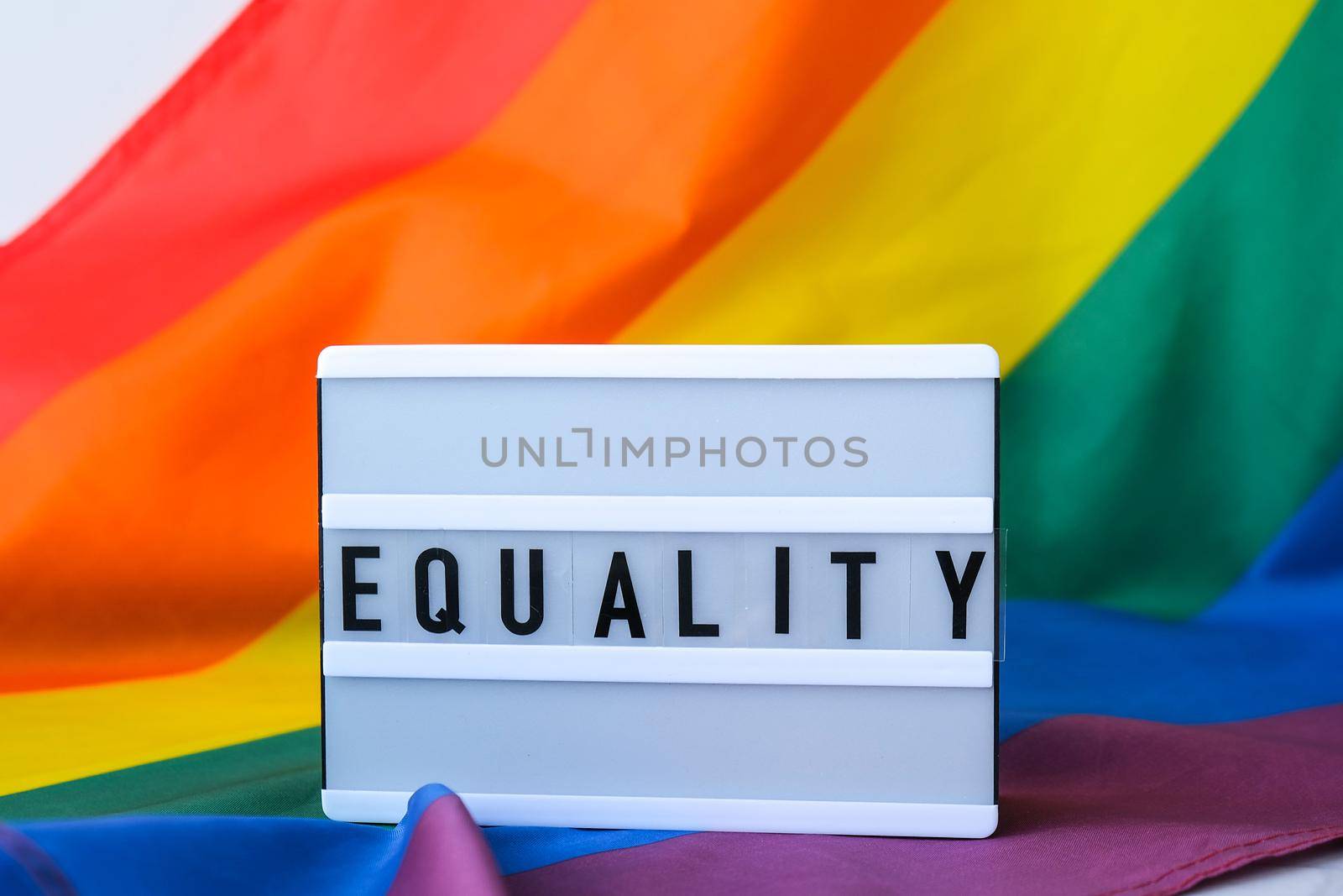 Rainbow flag with lightbox and text EQUALITY. Rainbow lgbtq flag made from silk material. Symbol of LGBTQ pride month. Equal rights. Peace and freedom. Support LGBTQ community