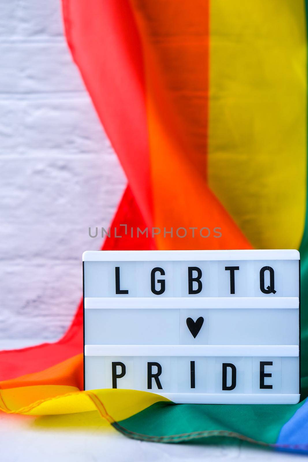 Rainbow flag with lightbox and text LGBTQ PRIDE. Rainbow lgbtq flag made from silk material. Symbol of LGBTQ pride month. Equal rights. Peace and freedom. Support LGBTQ community