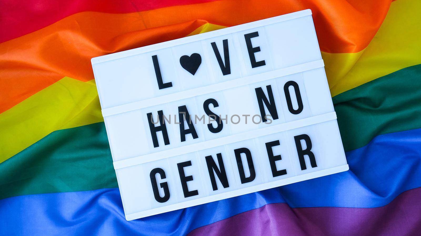 Rainbow flag with lightbox and text LOVE HAS NO GENDER. Rainbow lgbtq flag made from silk material. Symbol of LGBTQ pride month. Equal rights. Peace and freedom by anna_stasiia