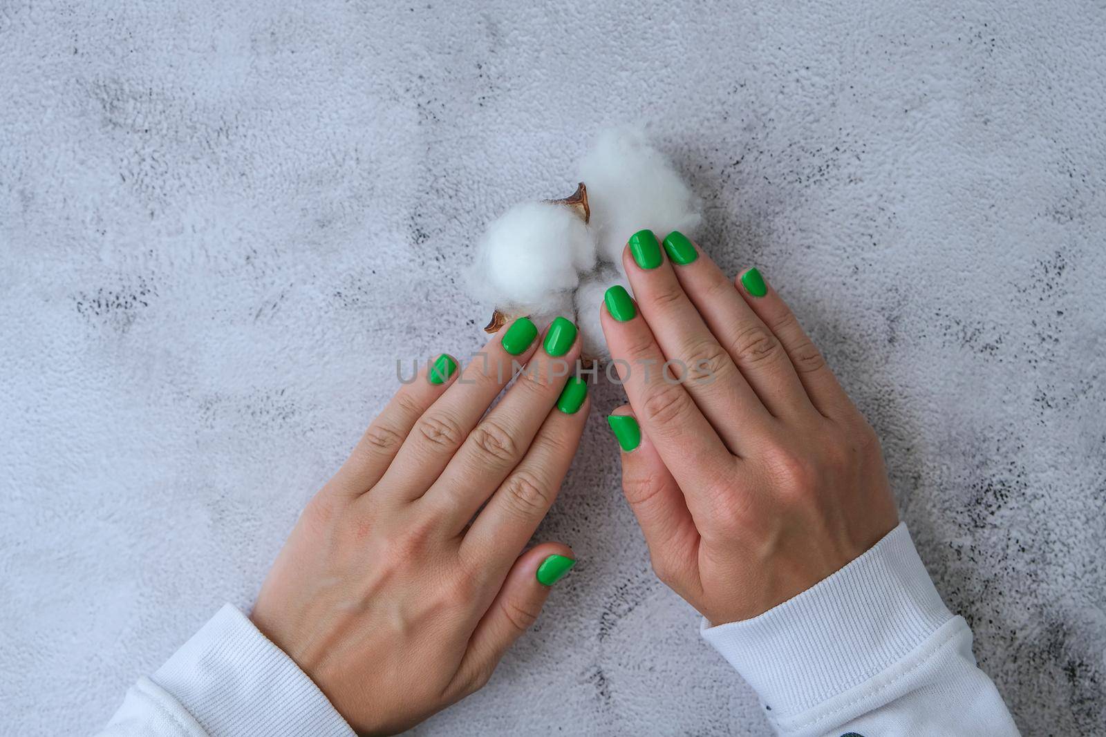 Manicured female hands with stylish green nails. Trendy modern design manicure. Gel nails. Skin care. Beauty treatment. Nail care. Wellness. Trendy colors.