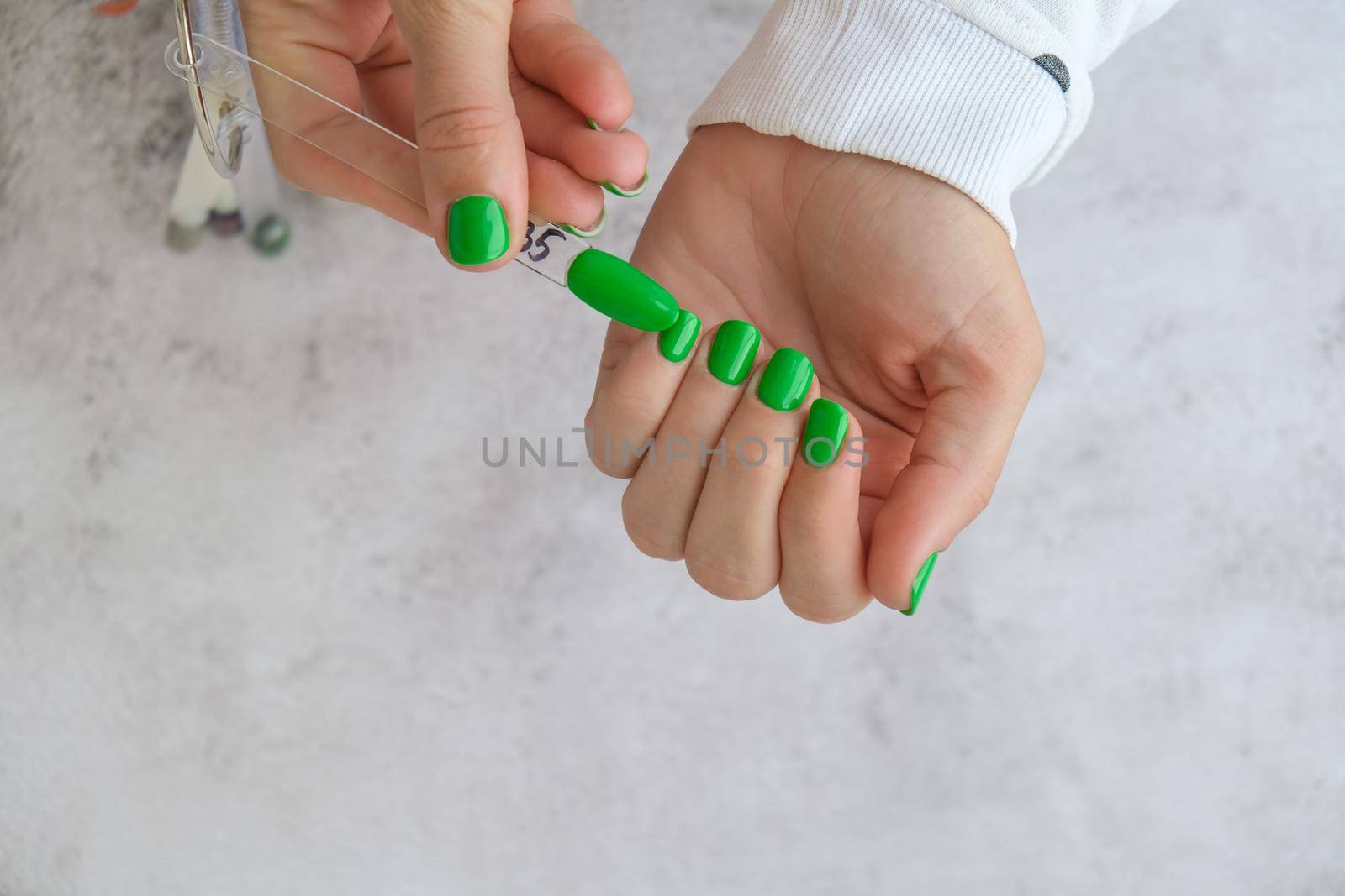 Manicured female hands with stylish green nails. Trendy modern design manicure. Gel nails. Skin care. Beauty treatment. Nail care. Wellness. Trendy colors.