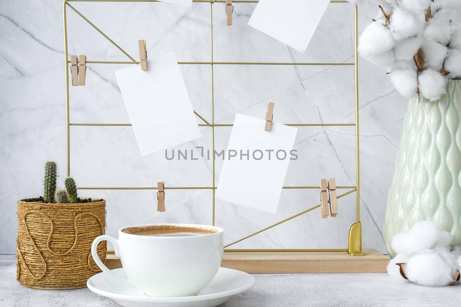 White home office room interior, bloggers workplace. Cup of coffee. Mood board with postcards and reminders mockup. Cotton branches in a vase, interior decoration. Feminine hipster office table decoration. Freelance workplace