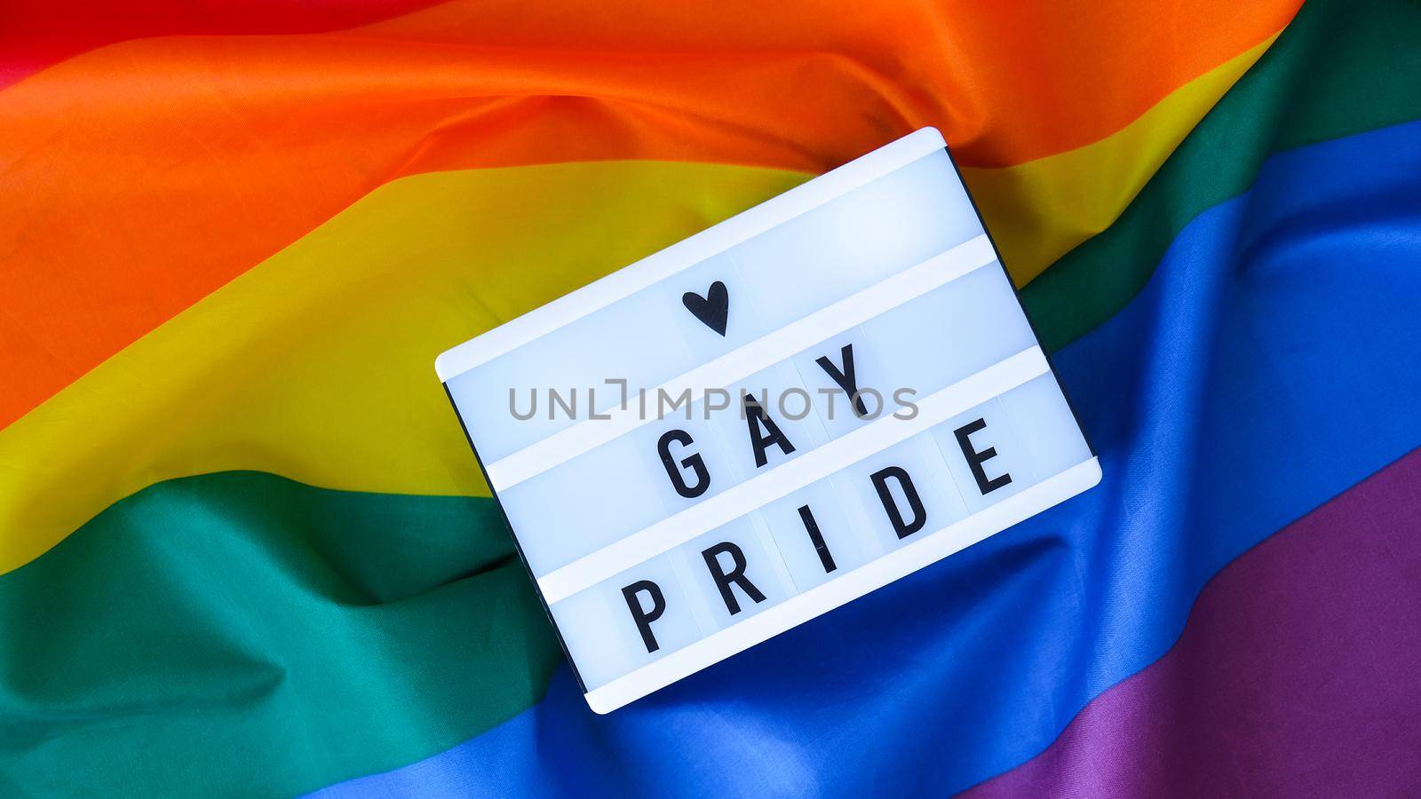 Rainbow flag with lightbox and text GAY PRIDE. Rainbow lgbtq flag made from silk material. Symbol of LGBTQ pride month. Equal rights. Peace and freedom. Support LGBTQ community