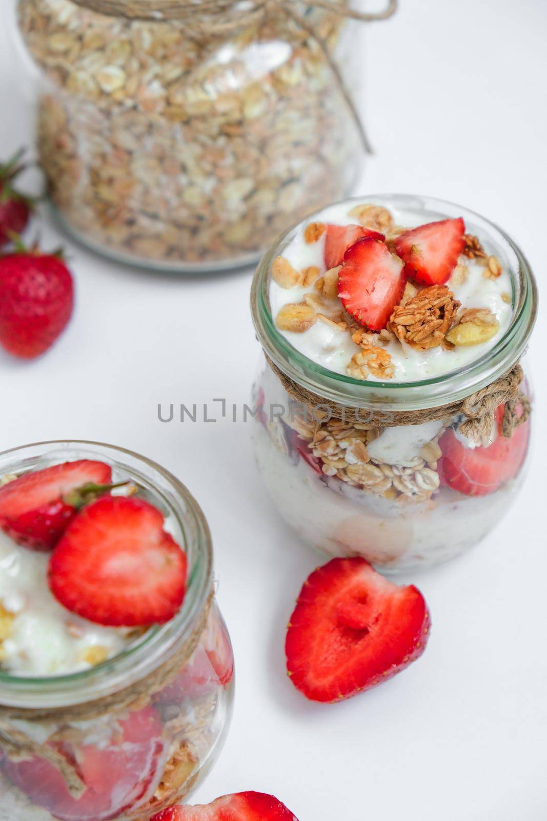 Healthy breakfast. Oatmeal Granola with greek yogurt and nuts strawberry muesli in jars on light background. Vegan, vegetarian and weight loss diet concept. Detox menu. Healthy eating food