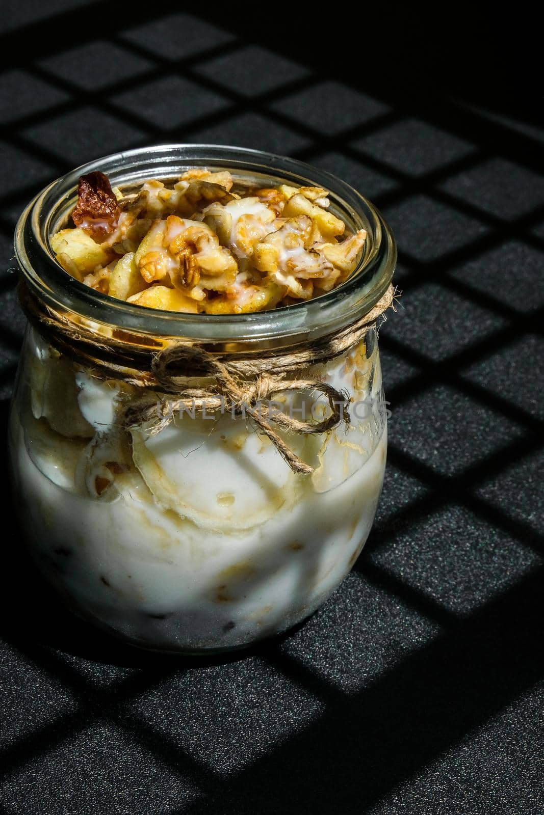 Healthy breakfast. Oatmeal Granola with greek yogurt and nuts banana muesli in jars on dark background. Trendy shadows Vegan, vegetarian and weight loss diet concept. Detox menu. Healthy eating food