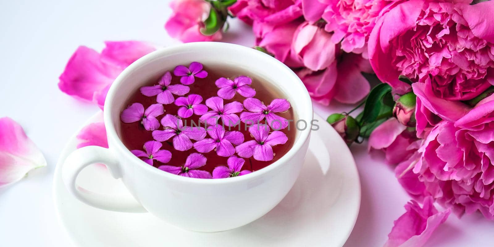Creative layout with pink peonies flowers and cup of tea on bright table. Spring Seasonal valentine, woman, mother, 8 march holiday, romance breakfast. Stylish blogger. Greeting card. Invitation. Blog post