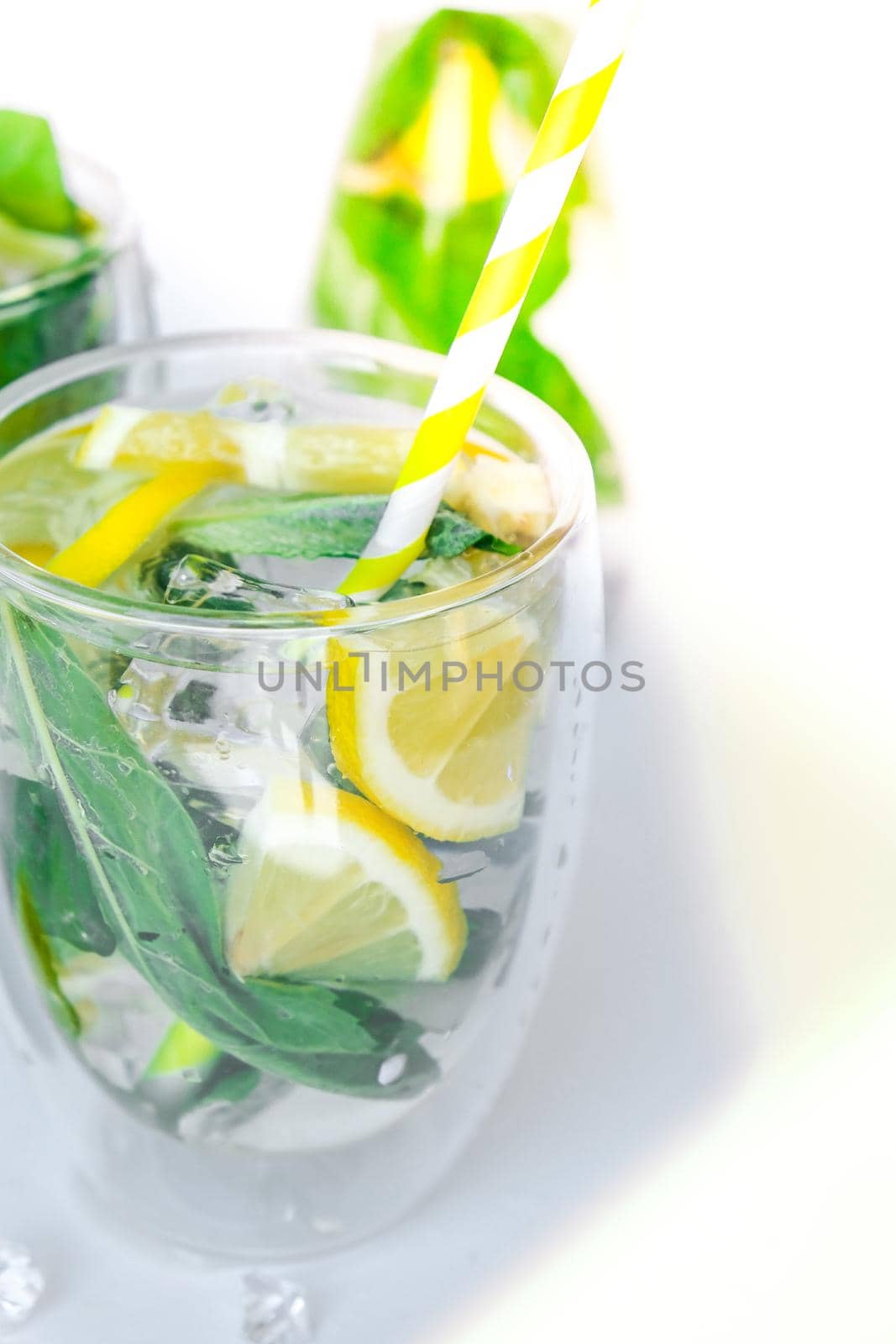 Mojito refreshing cocktail with eco paper drinking straw, alcohol drink. Lemonade with lemon and mint leaves on light background. Ice cubes. Summer refreshing detox drinks. Clean eating, healthy lifestyle concept, Diet. Nutrition.