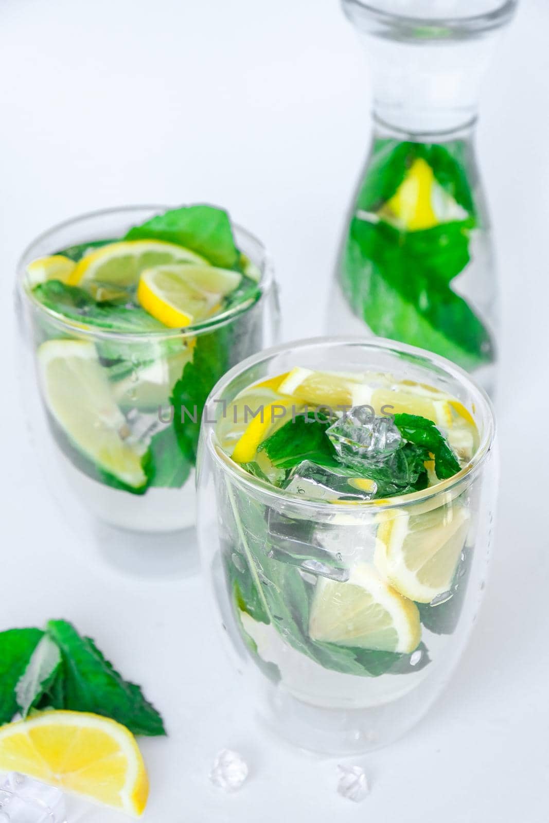 Mojito refreshing cocktail, alcohol drink. Lemonade with lemon and mint leaves on light background. Ice cubes. Summer refreshing detox drinks. Clean eating, healthy lifestyle concept, Diet. Nutrition.