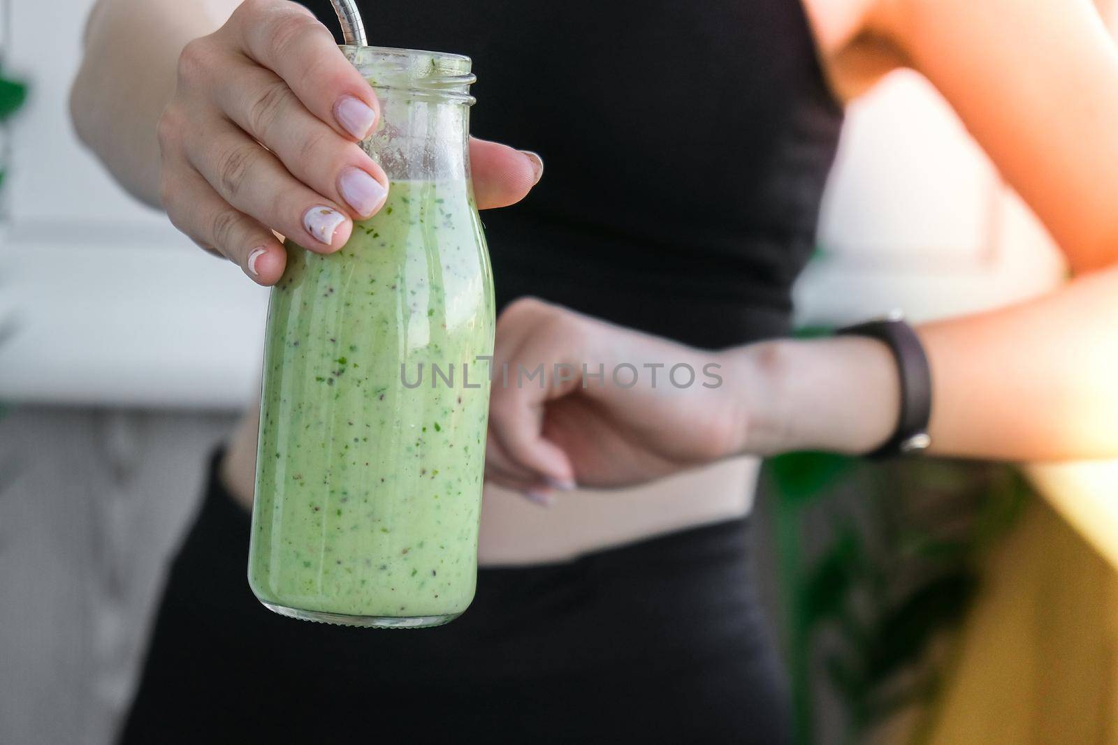 Young millenial blond woman drinking vegan smoothie drink detox. Woman doing yoga exercises checking smart sport watch at home. Clean eating, weight loss, healthy dieting food concept. Stay healthy. Wellness