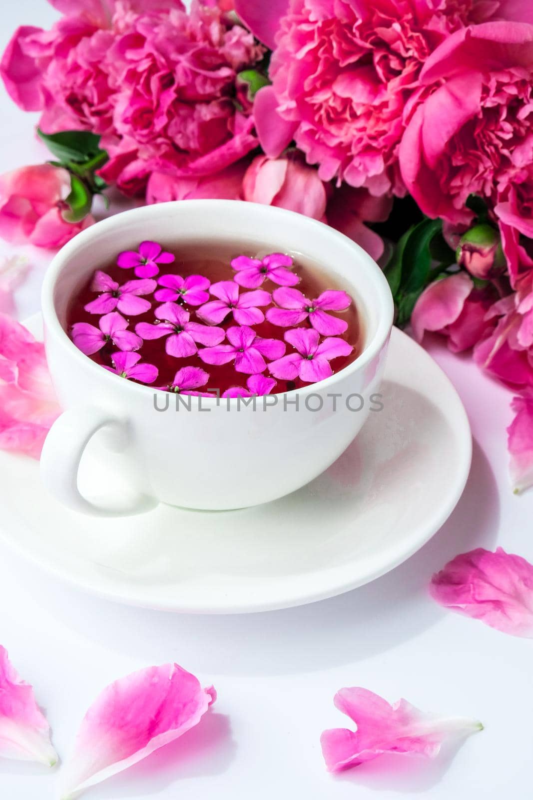 Creative layout with pink peonies flowers and cup of tea on bright table. Spring Seasonal valentine, woman, mother, 8 march holiday, romance breakfast. Stylish blogger. Greeting card. Invitation. Blog post
