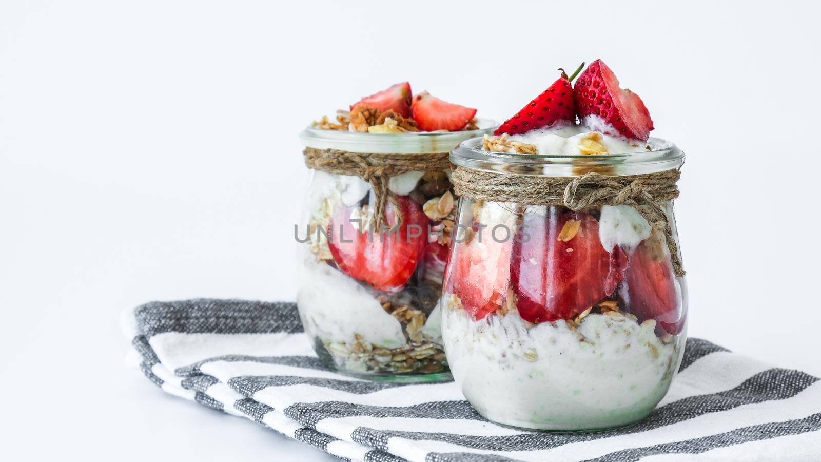 Healthy breakfast. Oatmeal Granola with greek yogurt and nuts strawberry muesli in jars on light background. Vegan, vegetarian and weight loss diet concept. Detox menu. Healthy eating food