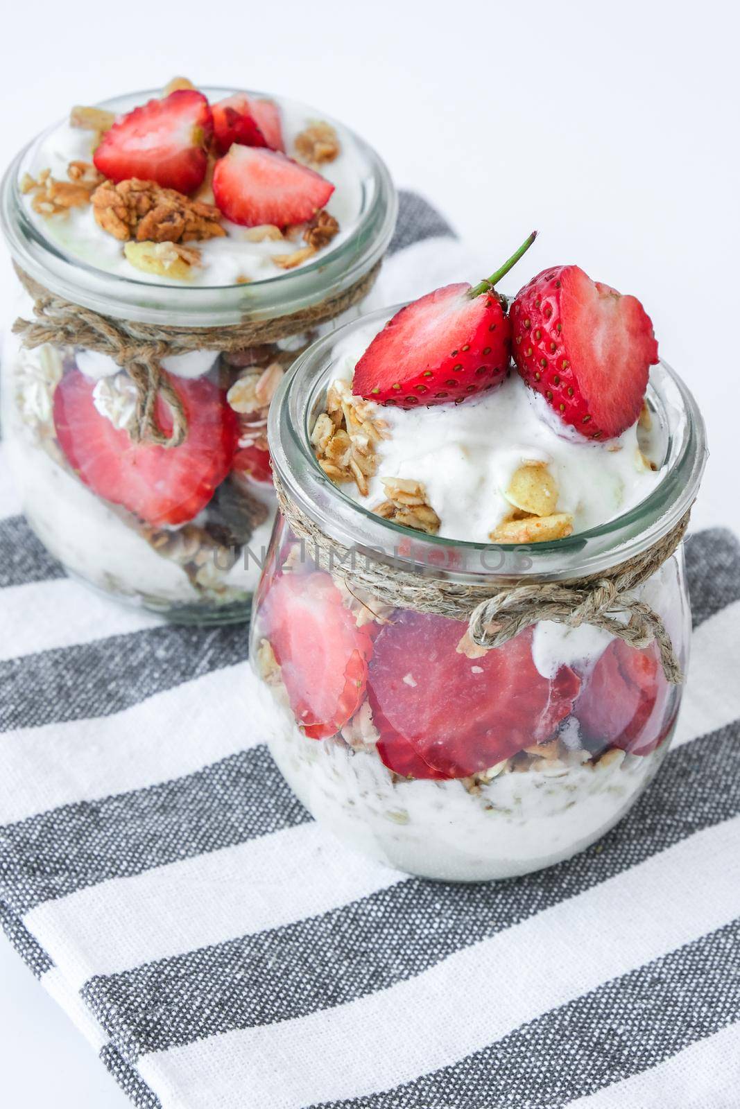 Healthy breakfast. Oatmeal Granola with greek yogurt and nuts strawberry muesli in jars on light background. Vegan, vegetarian and weight loss diet concept. Detox menu. Healthy eating food