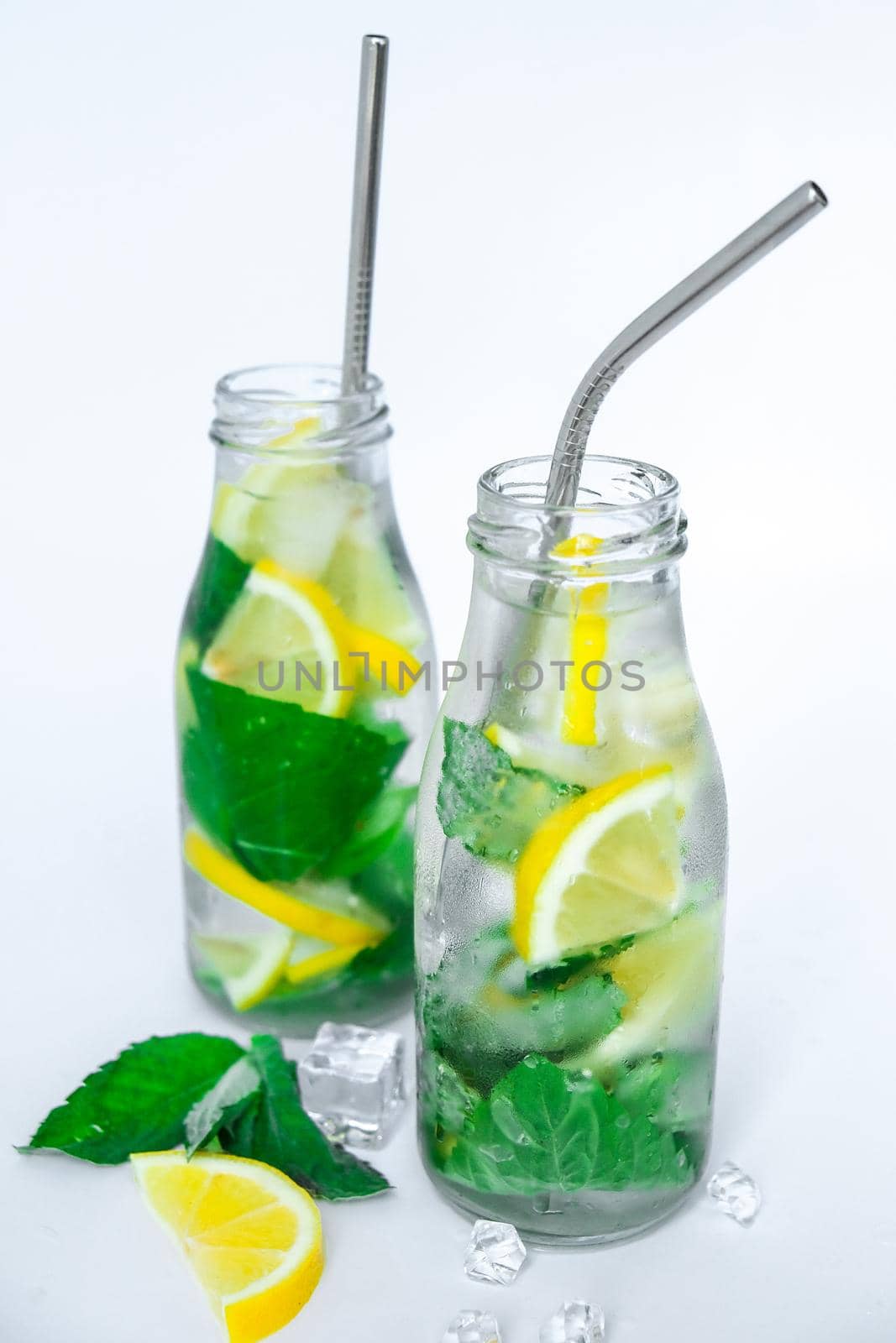 Mojito refreshing cocktail with eco metal drinking straw, alcohol drink. Lemonade with lemon and mint leaves on light background. Ice cubes. Summer refreshing detox drinks. Clean eating, healthy lifestyle concept, Diet. Nutrition.