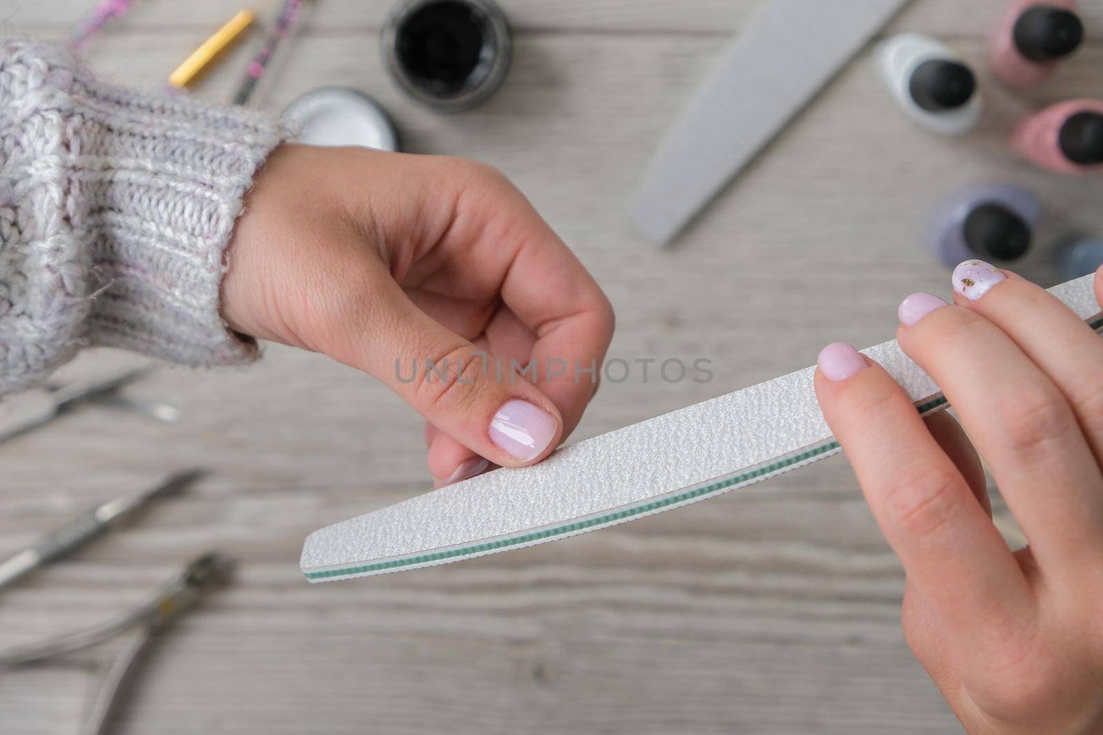 Modern female nude design manicure. Nail care, Self care. Do manicure by yourself while staying at home. Female hands and manicure tools. Spa salon. Professional Hardware Manicure. Procedure for the preparation of nails. Cuticle Pusher Remover. Nail file scissors