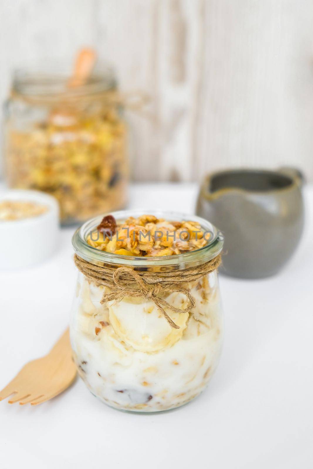 Healthy breakfast. Oatmeal Granola with greek yogurt and nuts banana muesli in jars on light background. Vegan, vegetarian and weight loss diet concept. Detox menu. Healthy eating food