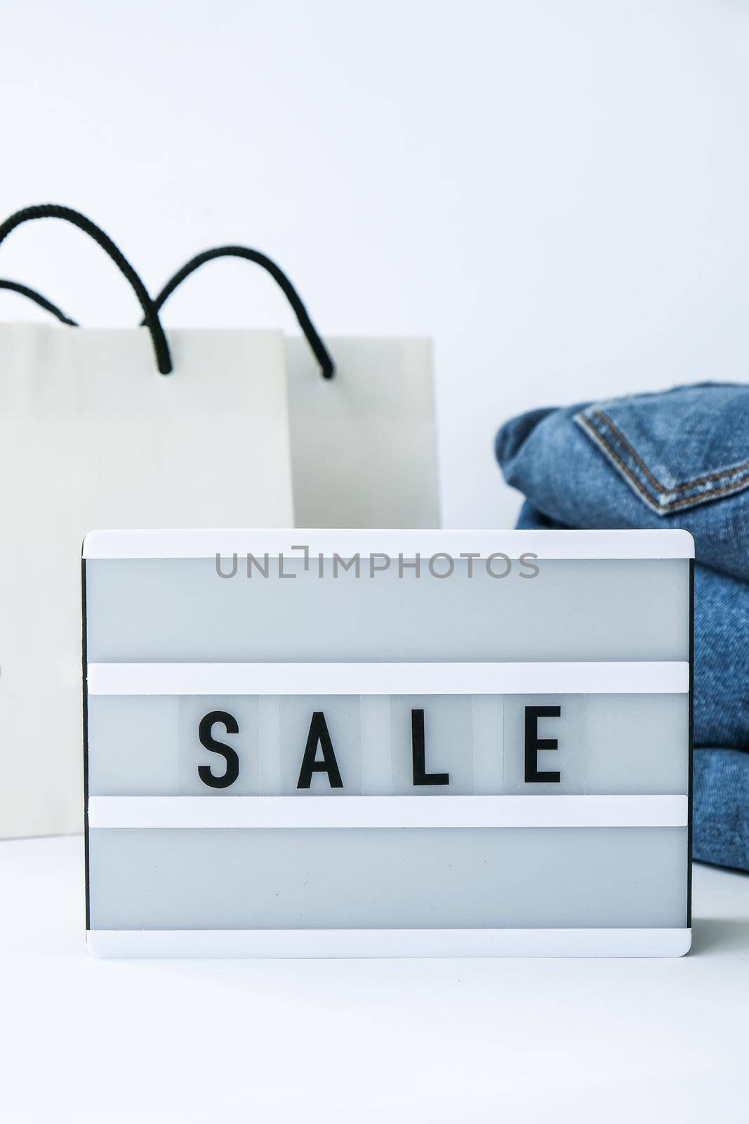 Light board with text SALE with paper shopping bags, jeans clothes. Big Sale online shopping concept. Promotion advertising. Holiday Cyber monday.