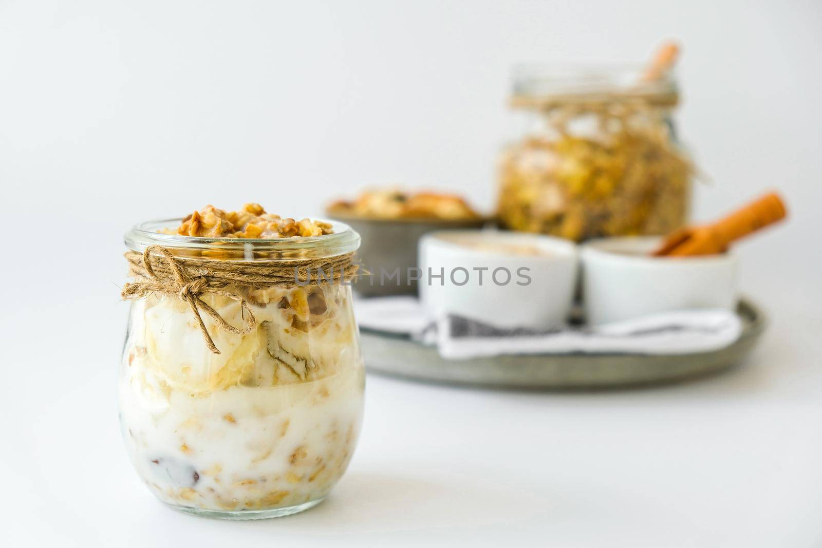 Healthy breakfast. Oatmeal Granola with greek yogurt and nuts banana muesli in jars on light background. Vegan, vegetarian and weight loss diet concept. Detox menu. Healthy eating food