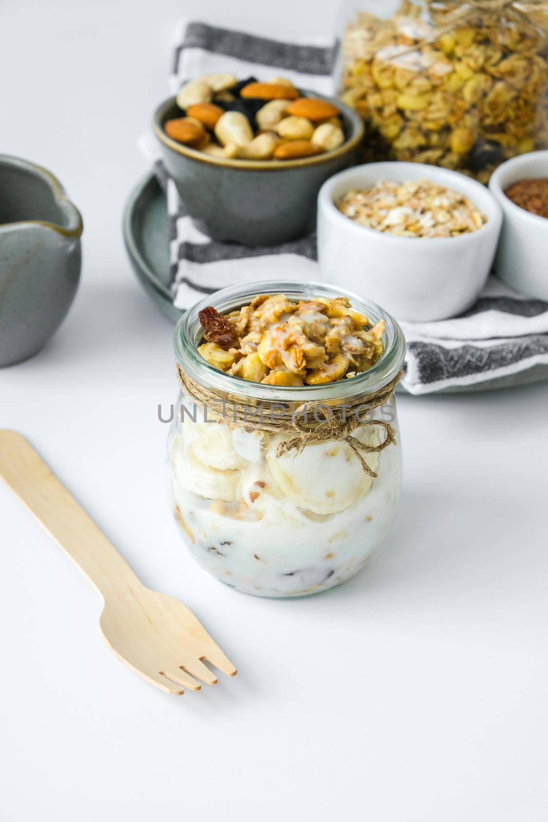 Healthy breakfast. Oatmeal Granola with greek yogurt and nuts banana muesli in jars on light background. Vegan, vegetarian and weight loss diet concept. Detox menu. Healthy eating food