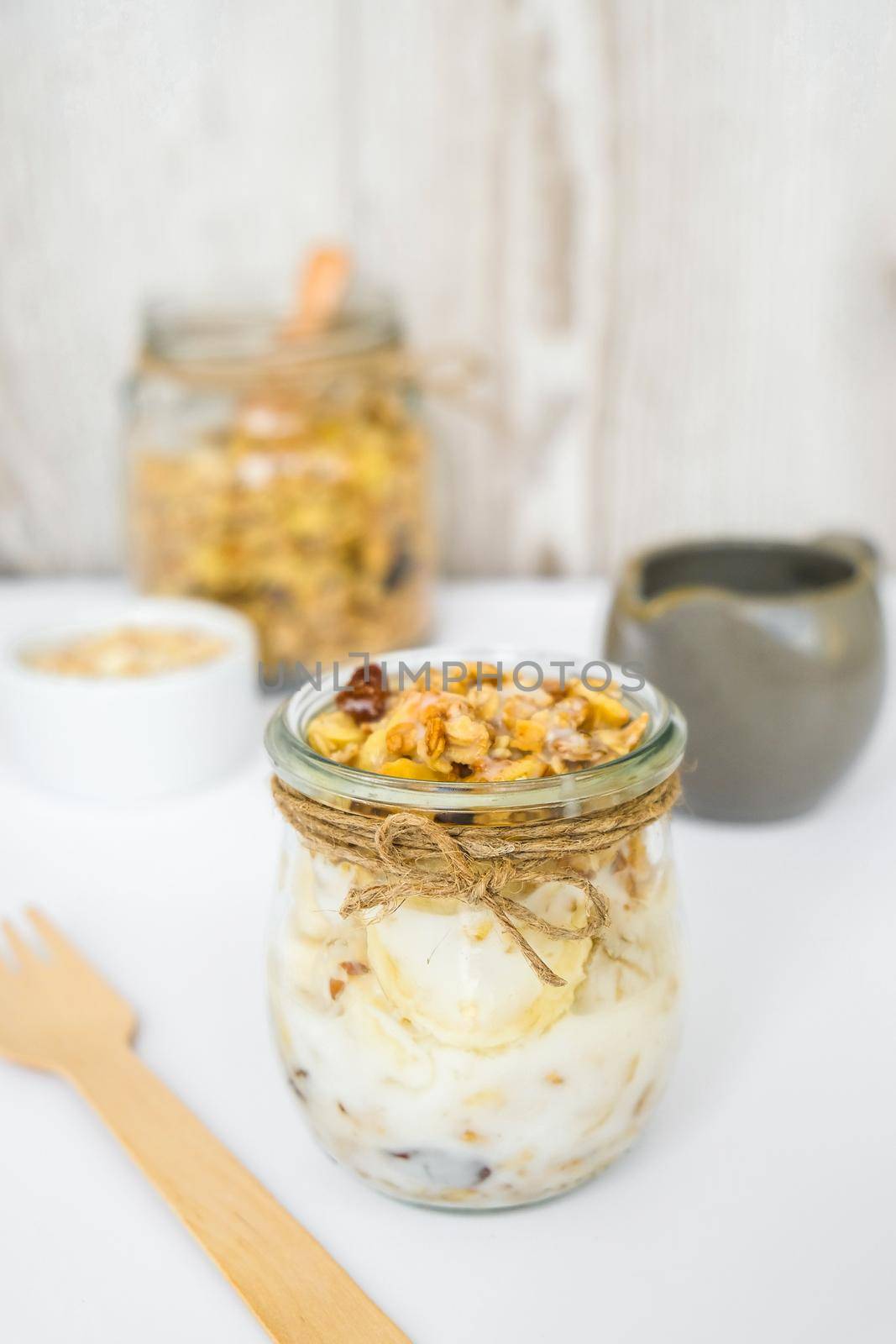 Healthy breakfast. Oatmeal Granola with greek yogurt and nuts banana muesli in jars on light background. Vegan, vegetarian and weight loss diet concept. Detox menu. Healthy eating food