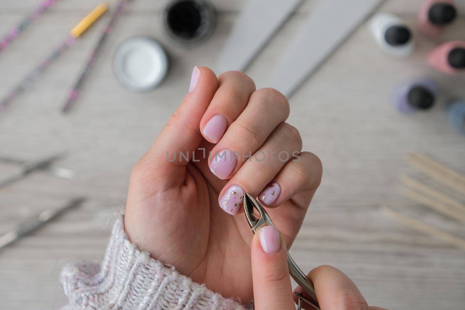 Modern female nude design manicure. Nail care, Self care. Do manicure by yourself while staying at home. Female hands and manicure tools. Spa salon. Professional Hardware Manicure. Procedure for the preparation of nails. Cuticle Pusher Remover. Nail file scissors