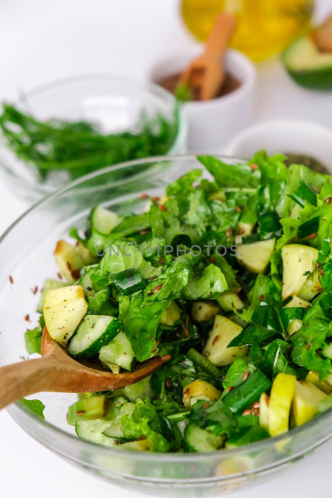 Salad of fresh green vegetables and herbs. Cooking healthy diet or vegetarian food. Step by step recipe. Healthy eating. Ingredients for salad. Raw food concept. A variety of organic fruits and vegetables with avocado. Vegan menu. Fresh spinach and green onion leaves, arugula. Flax seeds