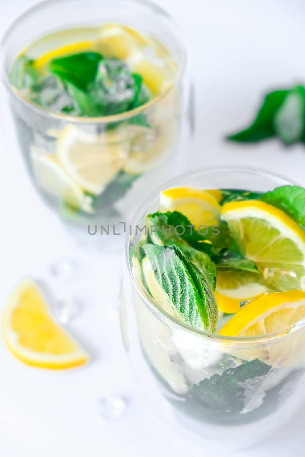 Mojito refreshing cocktail, alcohol drink. Lemonade with lemon and mint leaves on light background. Ice cubes. Summer refreshing detox drinks. Clean eating, healthy lifestyle concept, Diet. Nutrition.