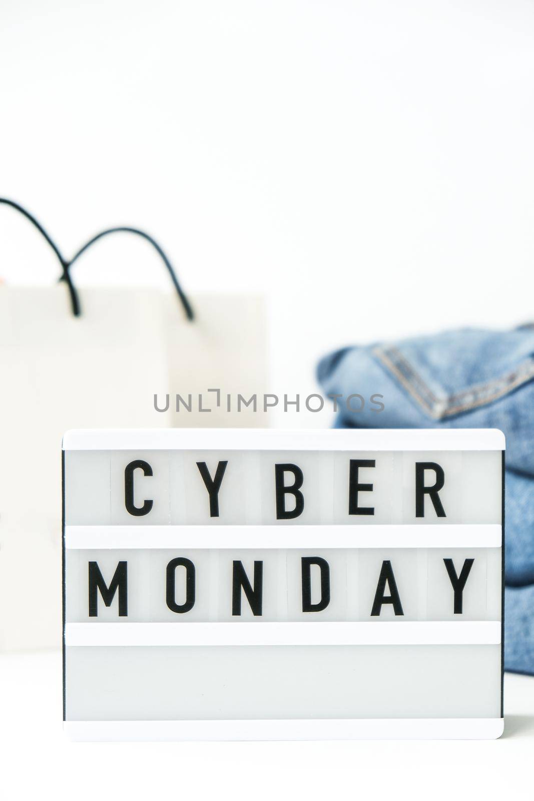 Light board with text CYBER MONDAY with paper shopping bags, jeans clothes. Big Sale online shopping concept. Promotion advertising. Holiday