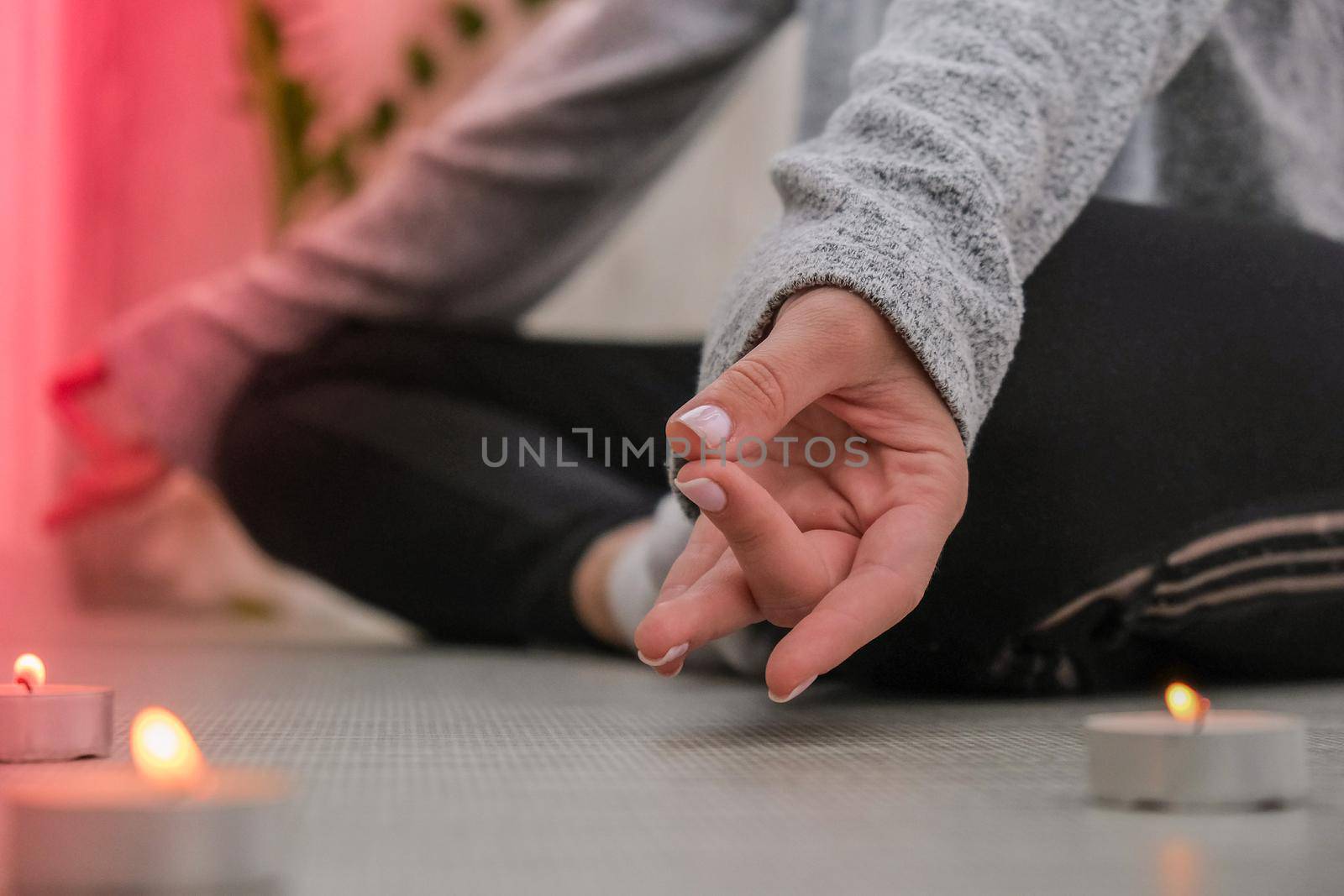 Close-up. Woman doing yoga exercise at home. Mindfulness meditation. Relax breathe easy pose gym healthy lifestyle concept. Burning candles light. Lotus asana. Atmosphere of relax and zen. Exercise to reach clarity of mind and perfect body. Padmasana