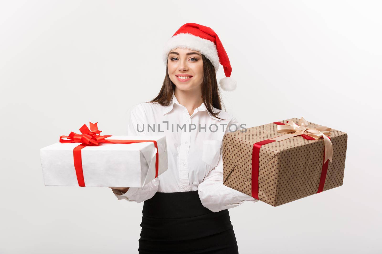 Christmas Concept - young happy caucasian business woman with santa hat giving a choice of gift boxs to camera with copy space on side.