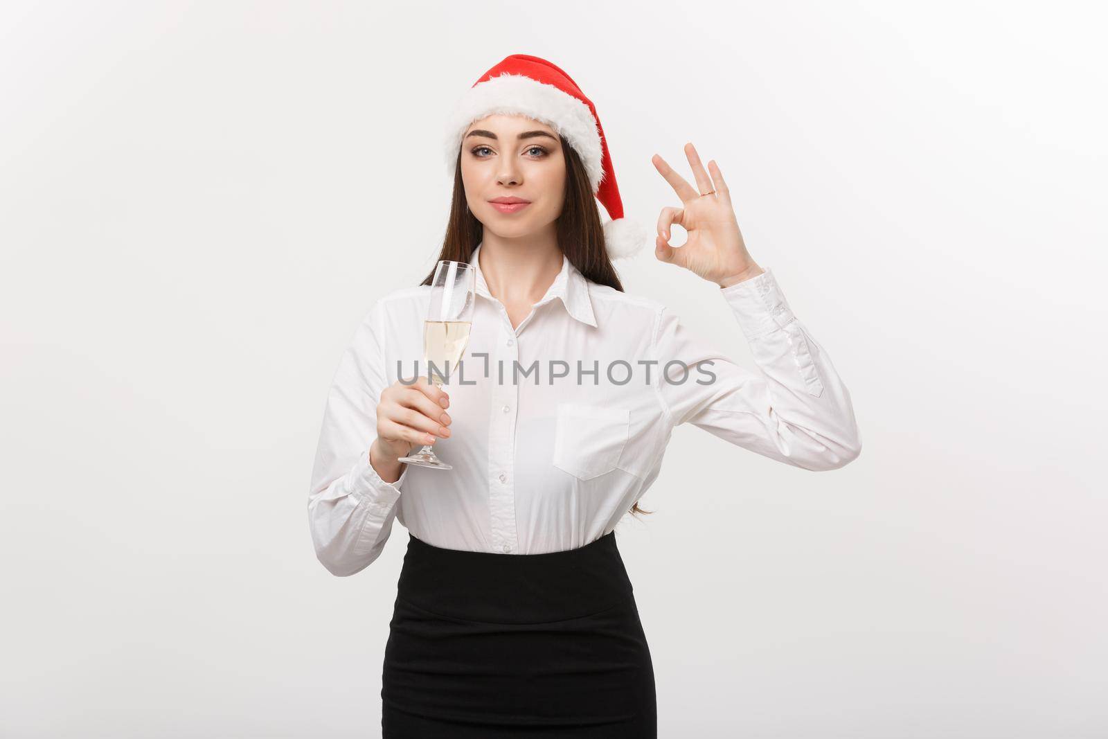 Christmas Celebration - Young beautiful business woman celebrating christmas with glass of champagne and showing ok sign. by Benzoix