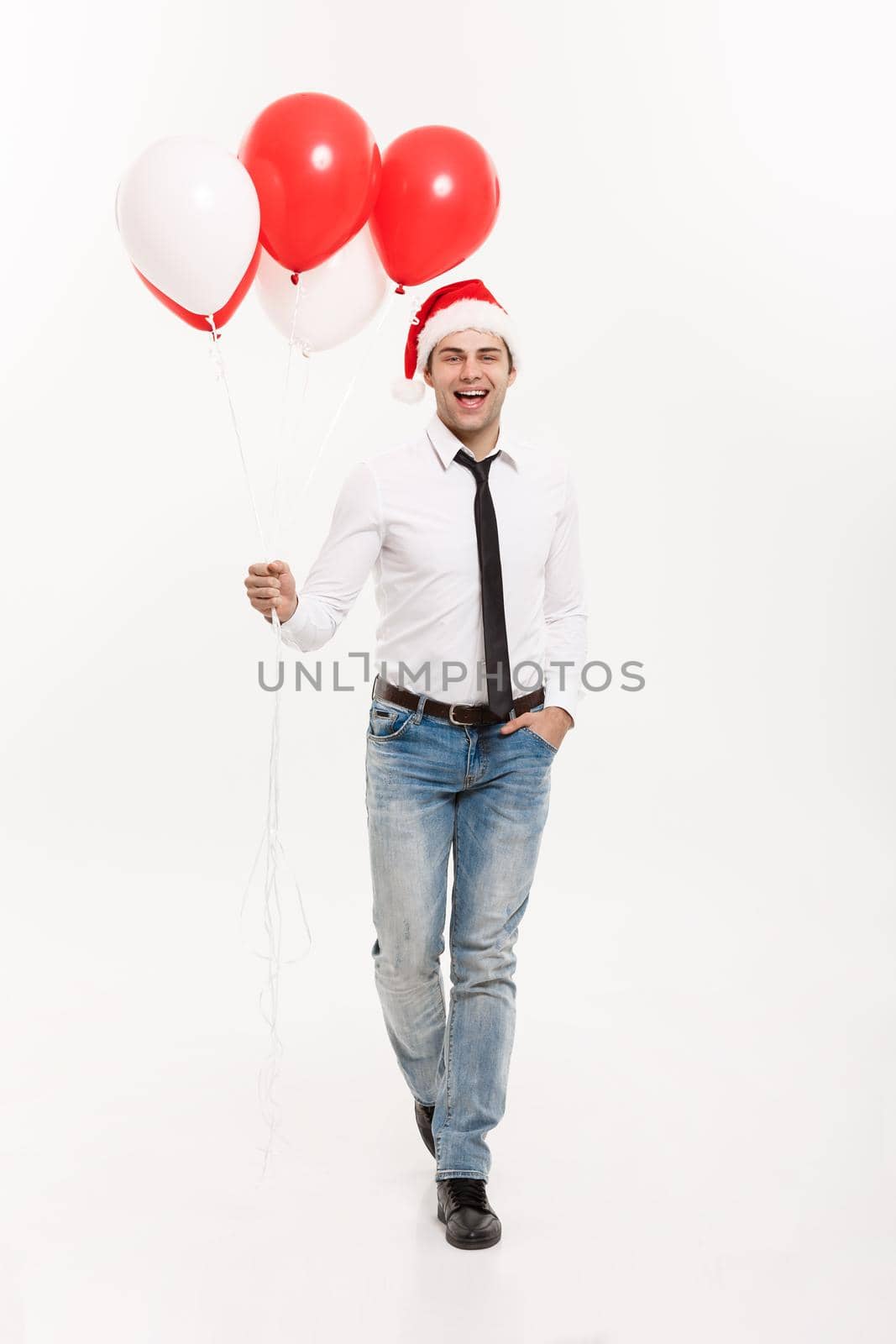 Christmas Concept - Handsome happy Business man walking with red balloon celebrate merry christmas and happy new year wear santa hat. by Benzoix