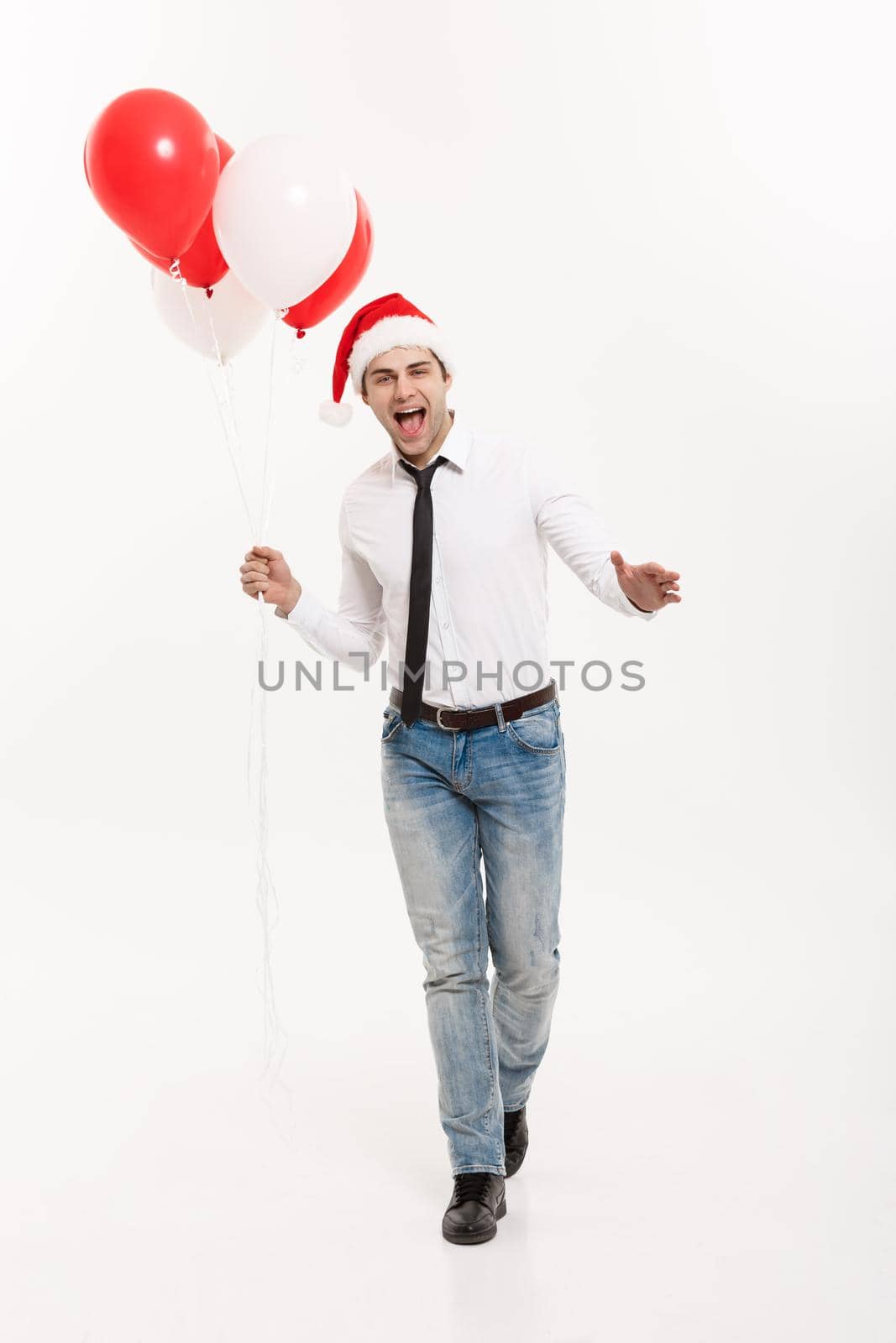 Christmas Concept - Handsome happy Business man walking with red balloon celebrate merry christmas and happy new year wear santa hat.