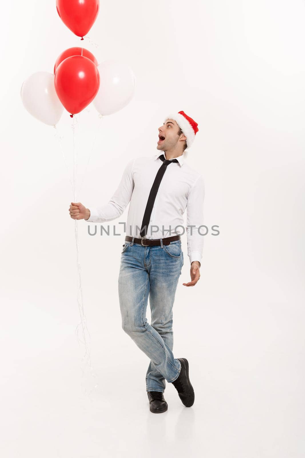 Christmas Concept - Handsome happy Business man walking with red balloon celebrate merry christmas and happy new year wear santa hat. by Benzoix