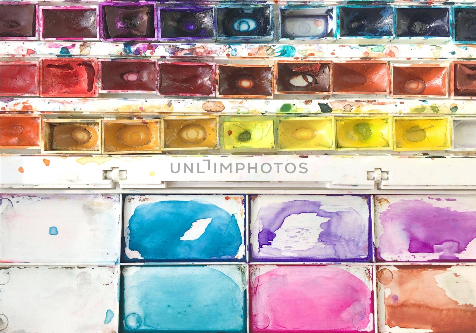 Used watercolor paints with palette top view. Set of old multi colored watercolor in plastic box with samples of paint flat lay