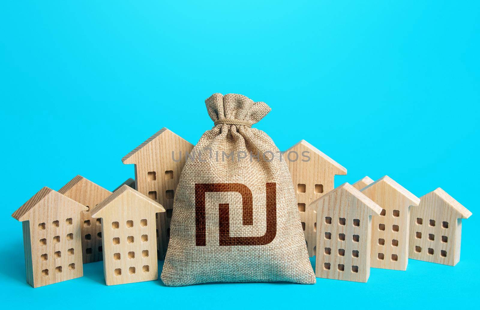 Israeli shekel money bag among town houses figurines. Rich city. Rental business. Realtor services. Sale of real estate. property taxes. Investment in city development. Municipal budgeting.
