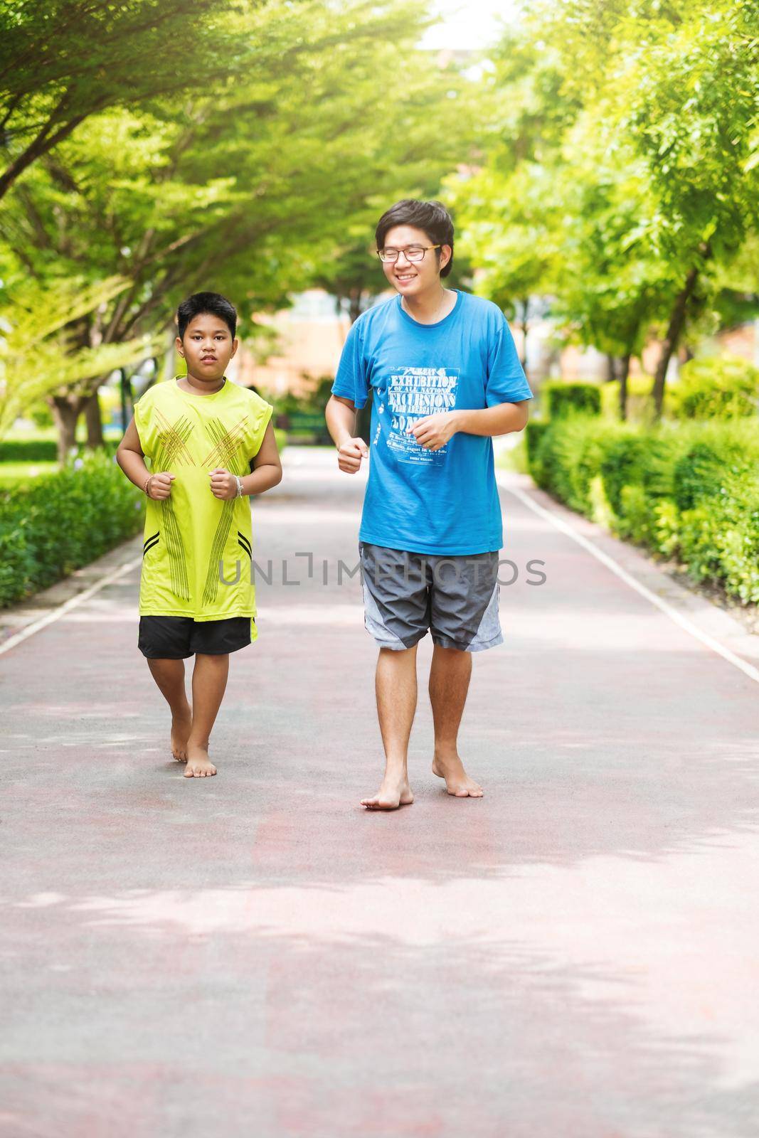 Asian couple of brother run together in park. by Benzoix