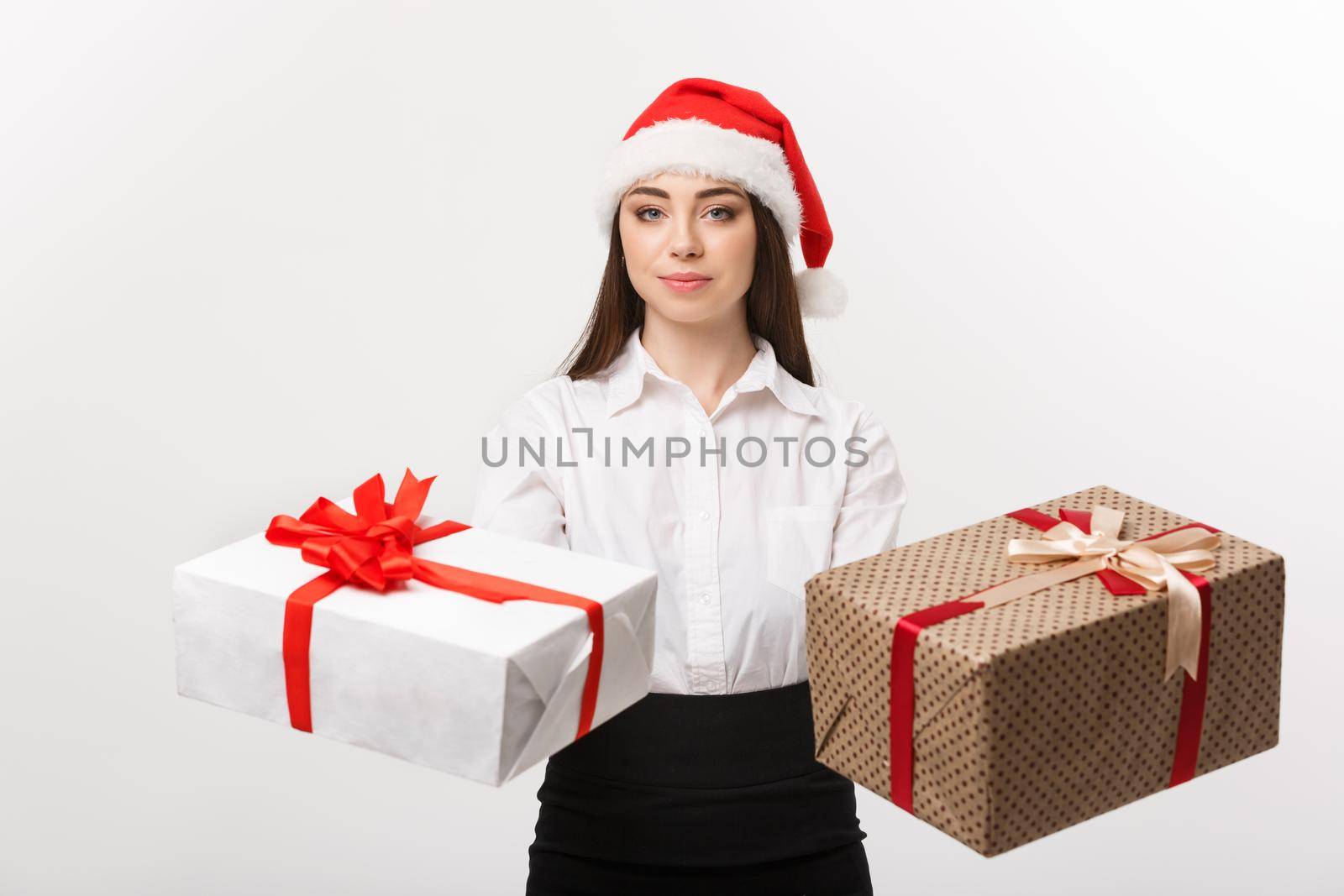 Christmas Concept - young happy caucasian business woman with santa hat giving a choice of gift boxs to camera with copy space on side.